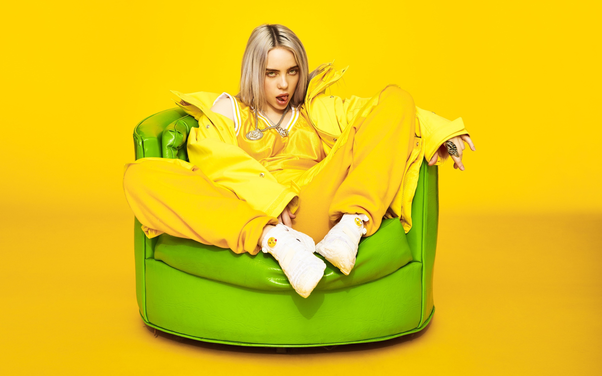 Певица Билли Айлиш сидит в кресле на желтом фоне