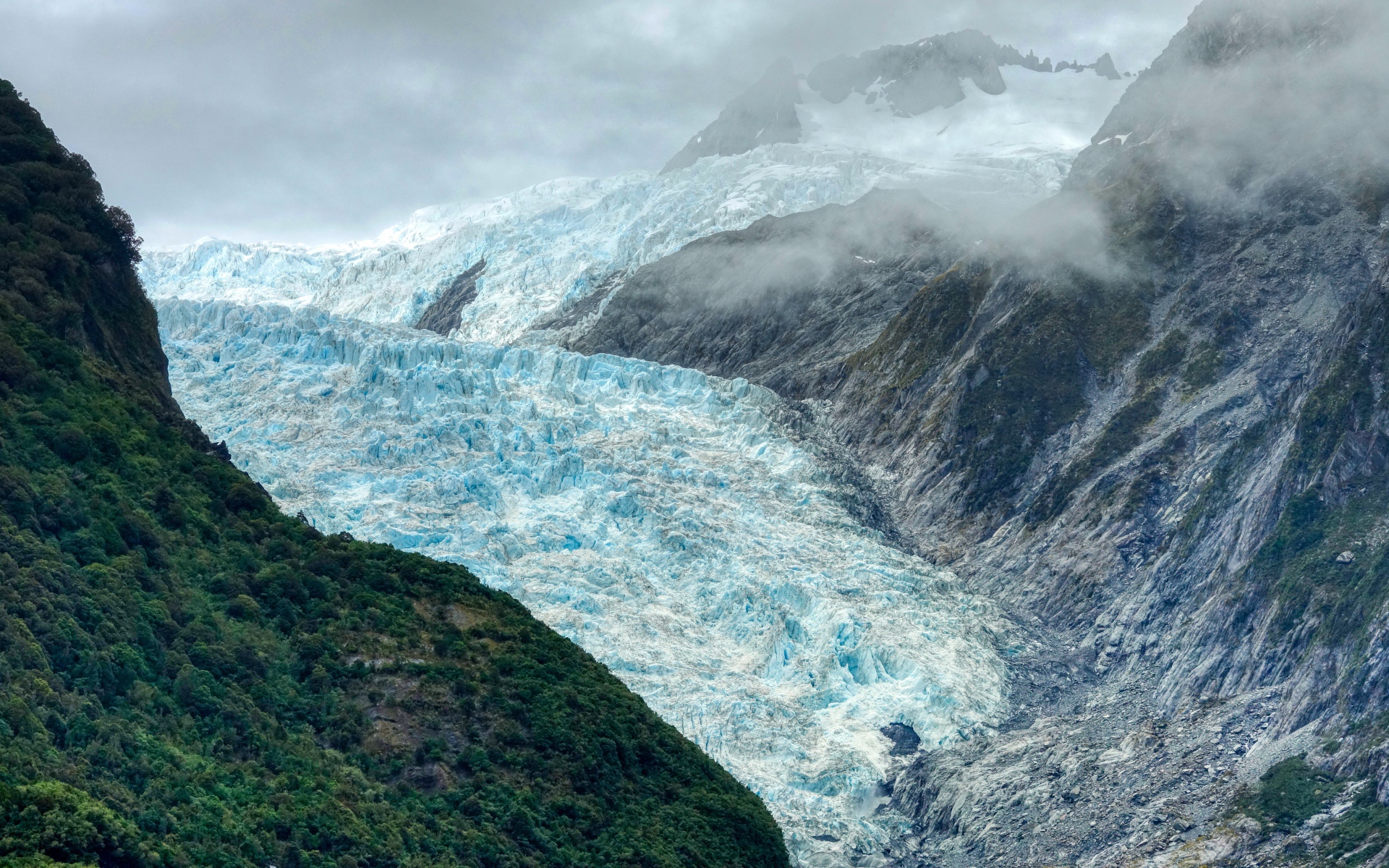 Голубой ледник между скал под грозовым небом