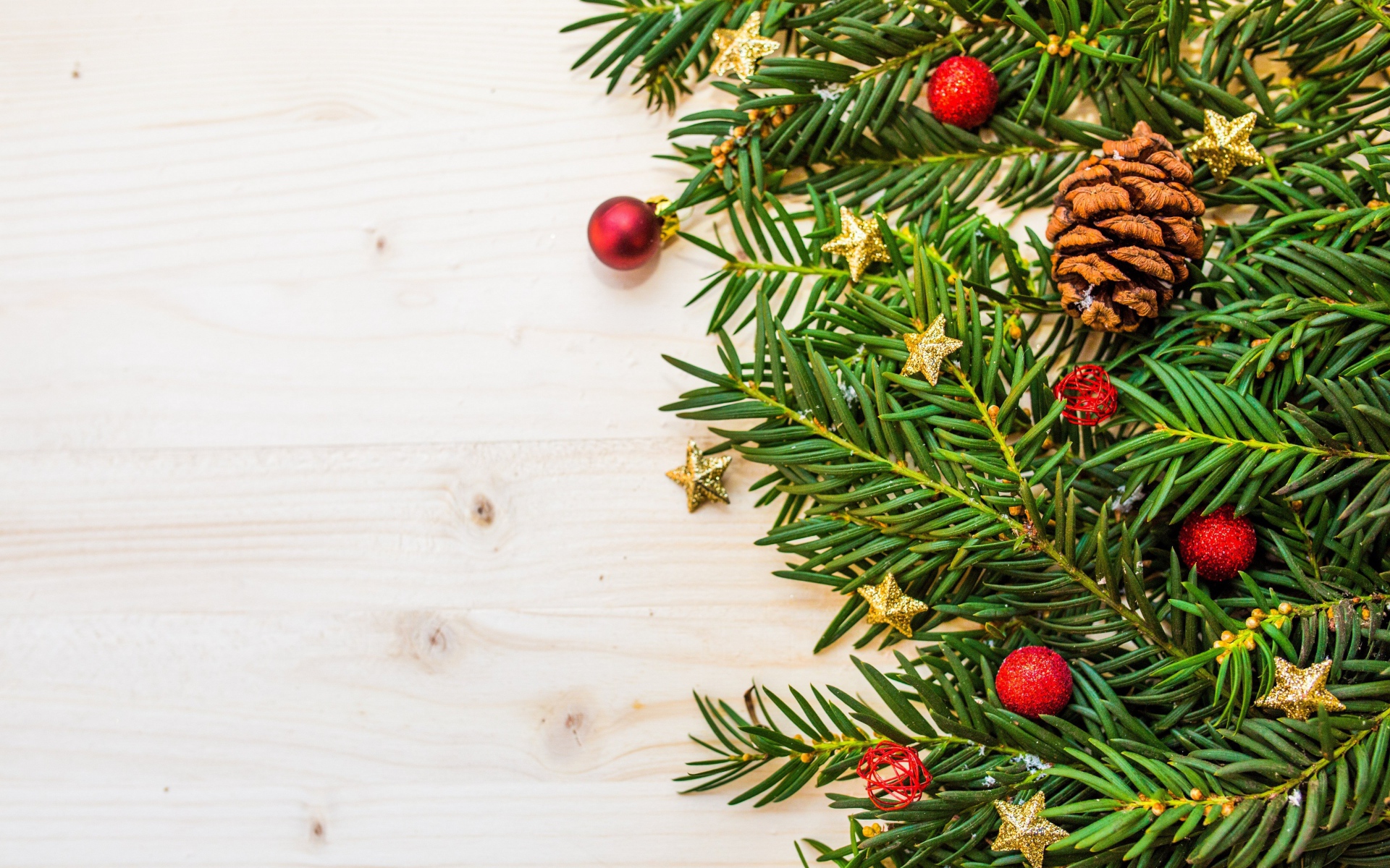 Зеленые ветки ели, шишки и игрушки на белом фоне