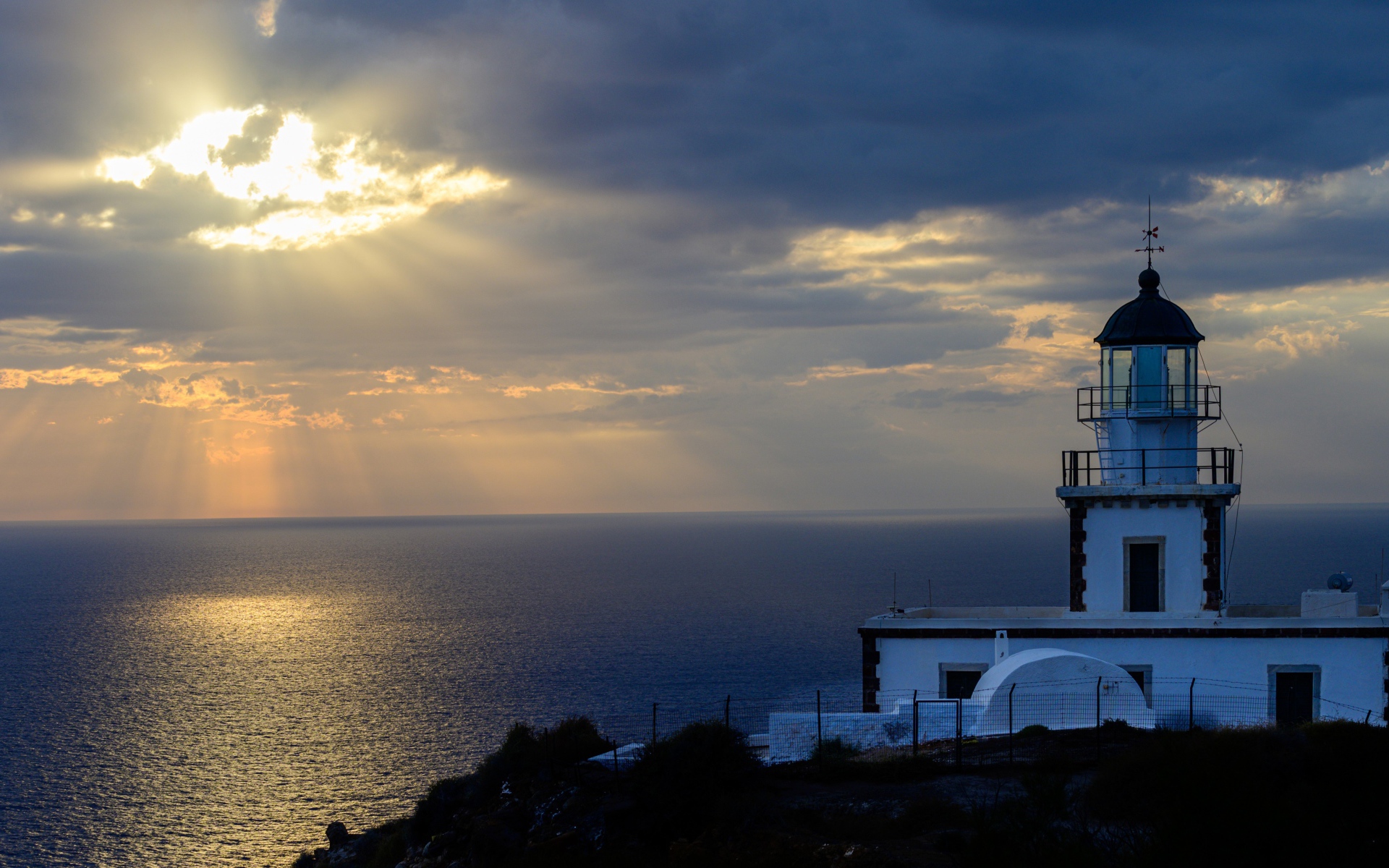 Белый маяк на берегу в лучах солнца у моря 