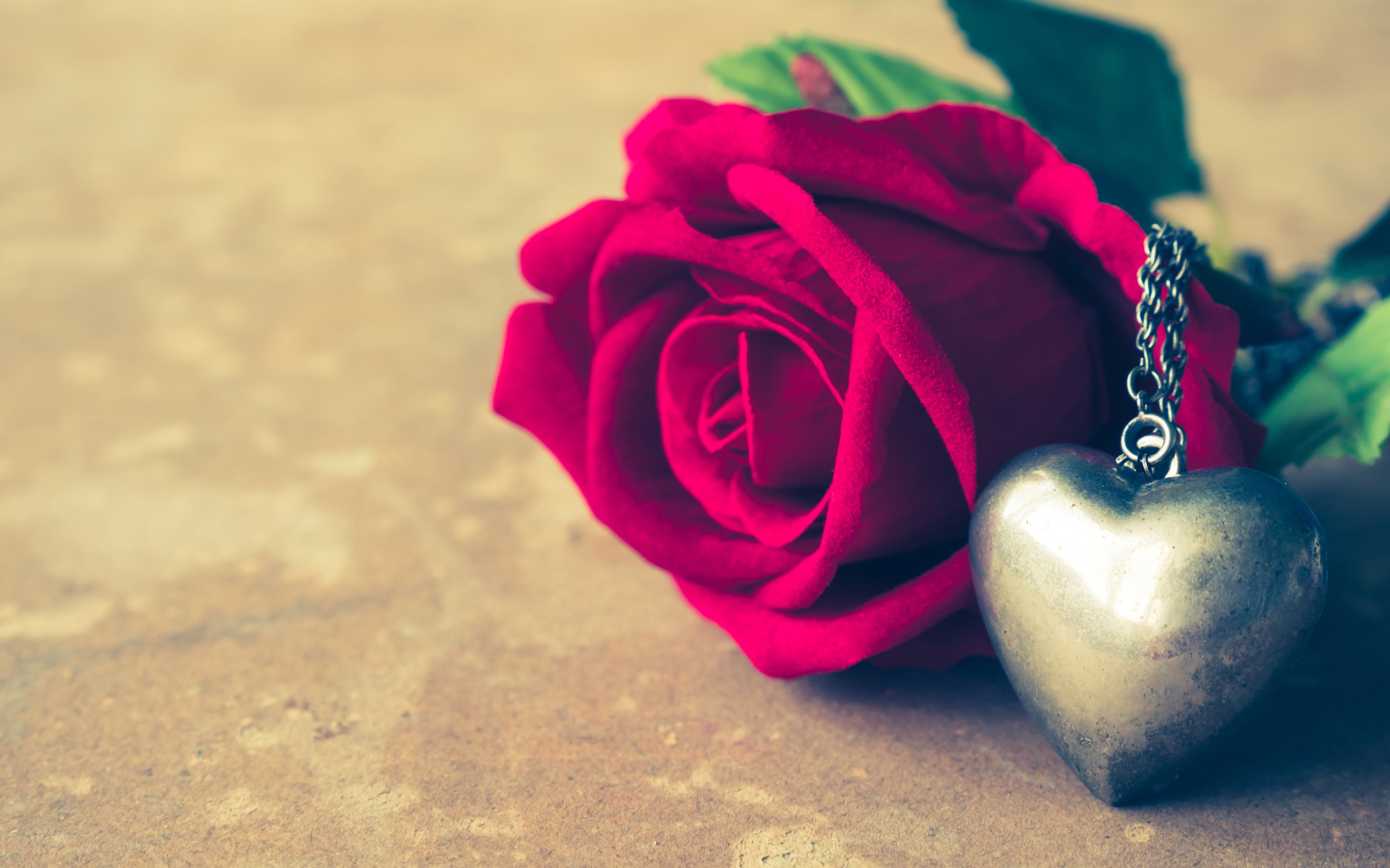 Искусственная роза с кулоном на столе