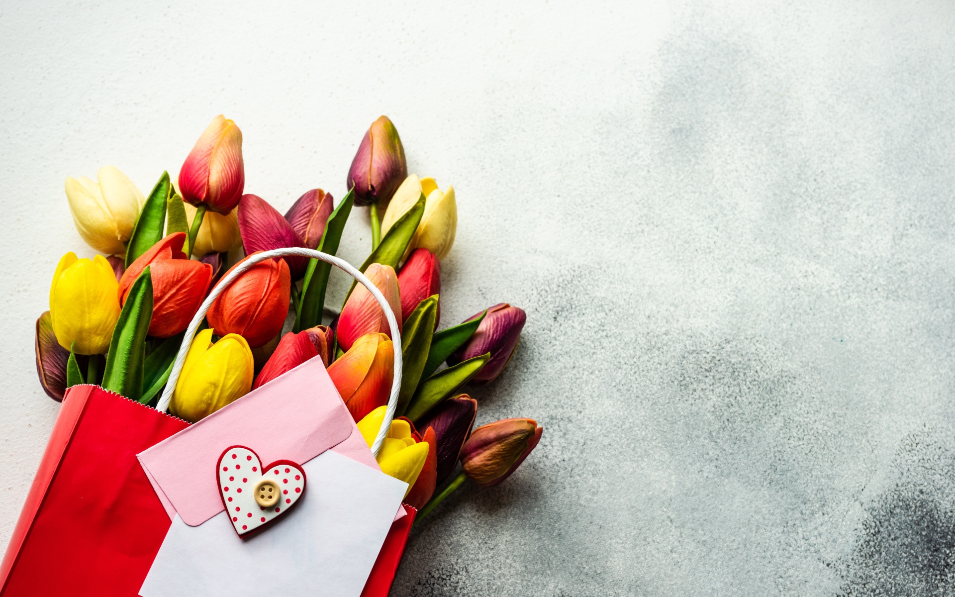 Букет разноцветных тюльпанов с письмом на сером фоне