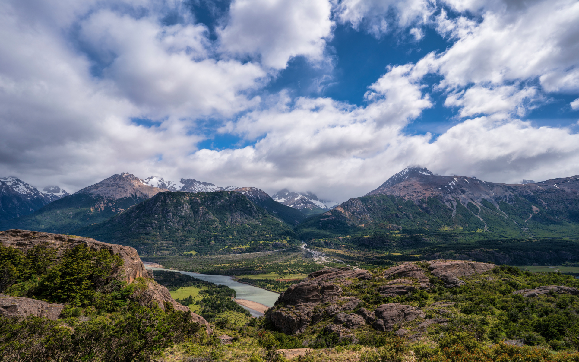 Белые облака в голубом небе над покрытыми зеленью горами
