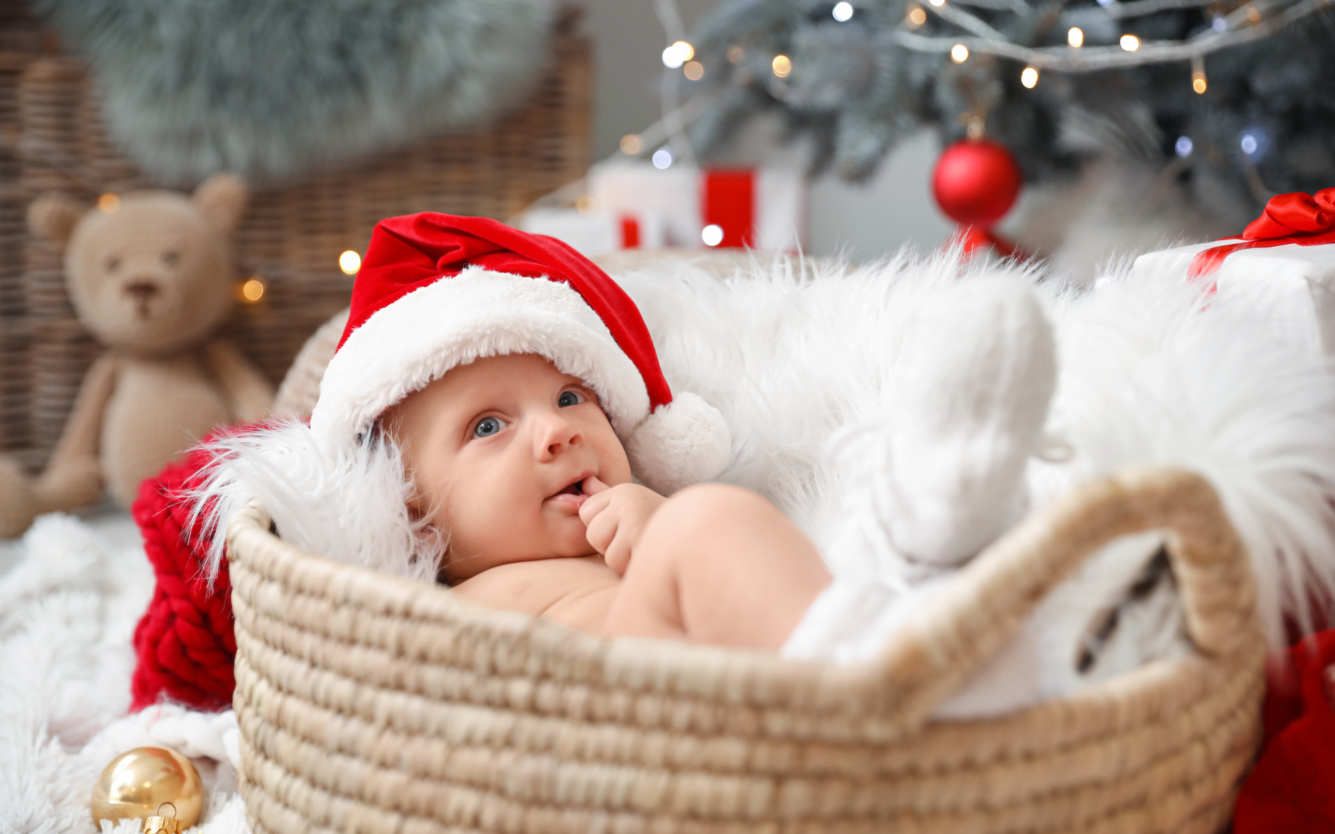 Милый малыш в шапке Санта Клауса лежит в корзине