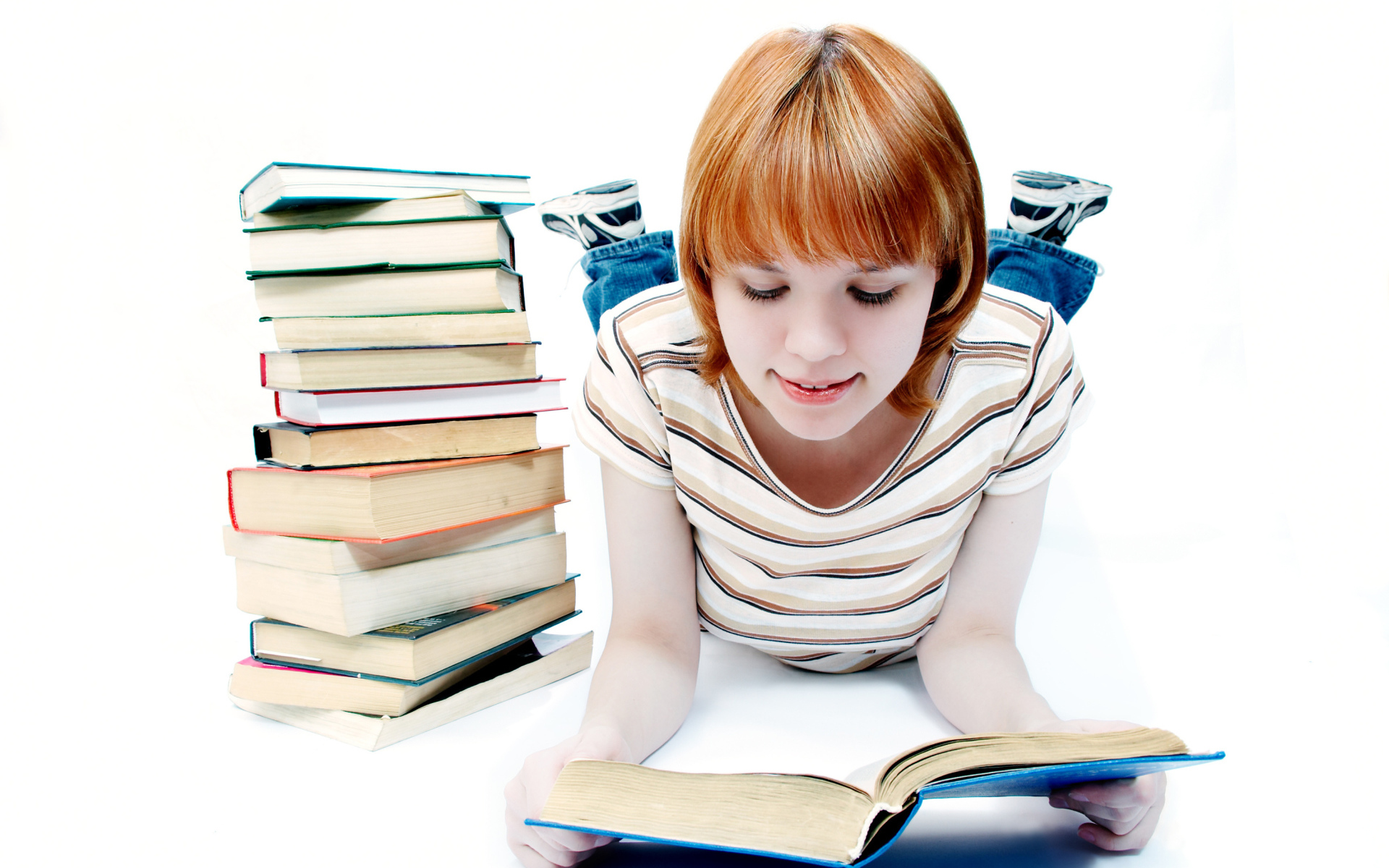 Рыжеволосая девочка школьница читает книги на белом фоне 