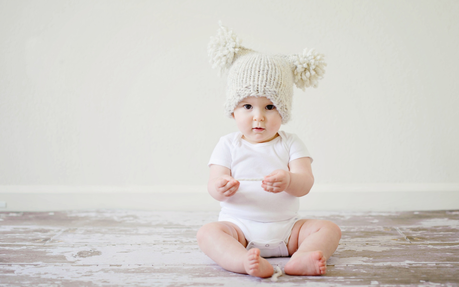 Маленький грудной ребенок в боди с шапкой на голове