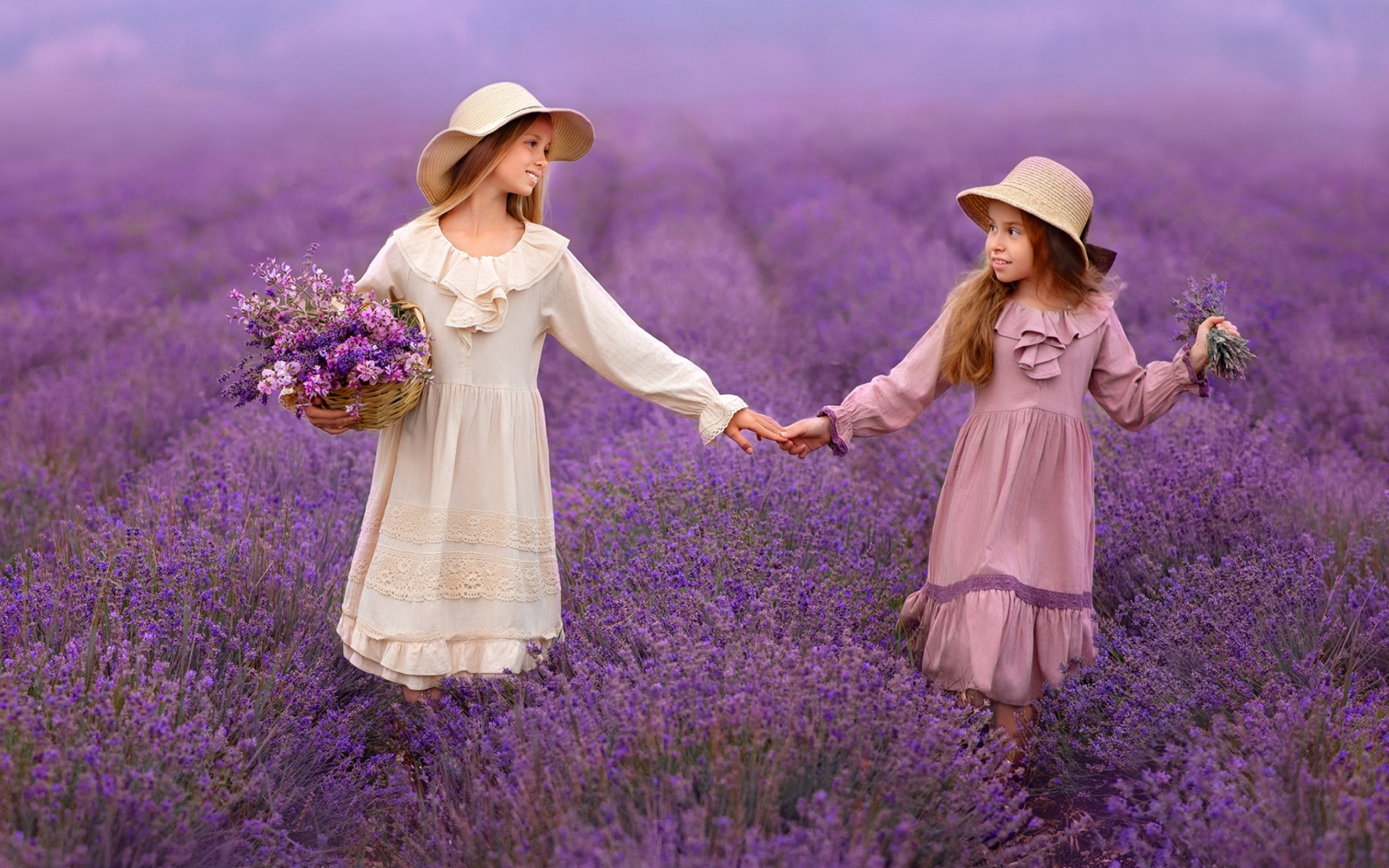 Две маленькие девочки идут по лавандовому полю 