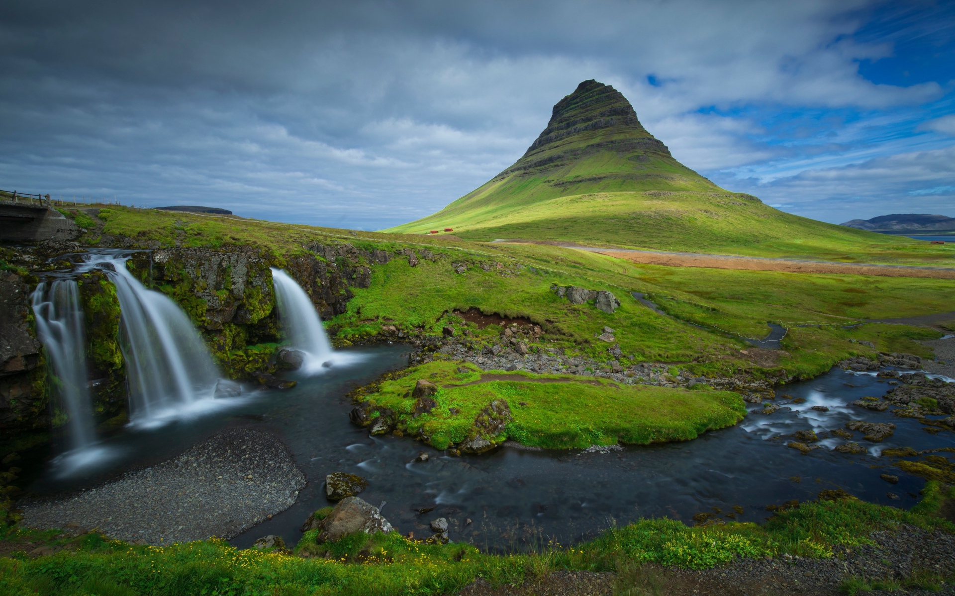 Вид на маленький водопад и покрытую зеленью гору, Исландия