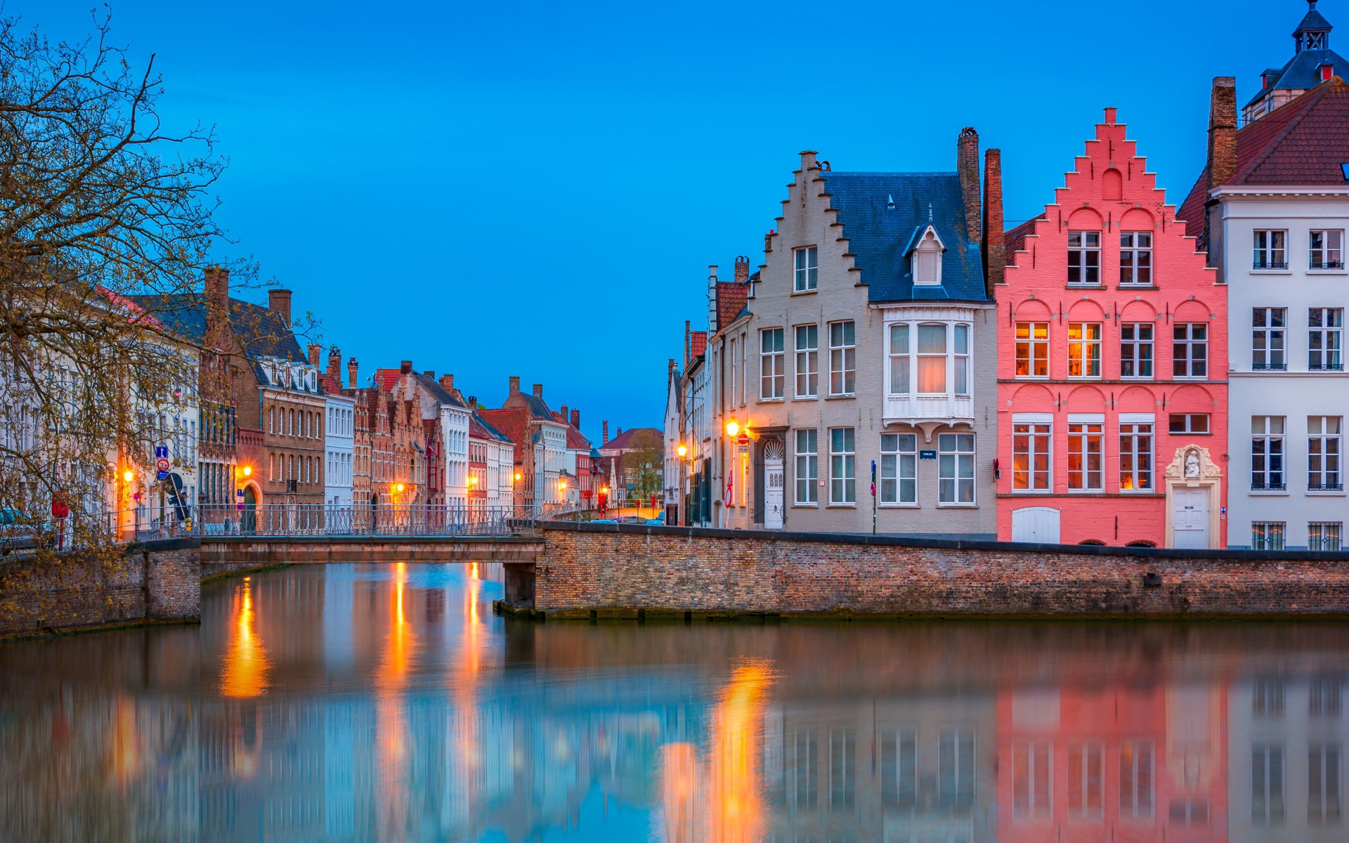 Большие дома и фонари отражаются в воде канала вечером