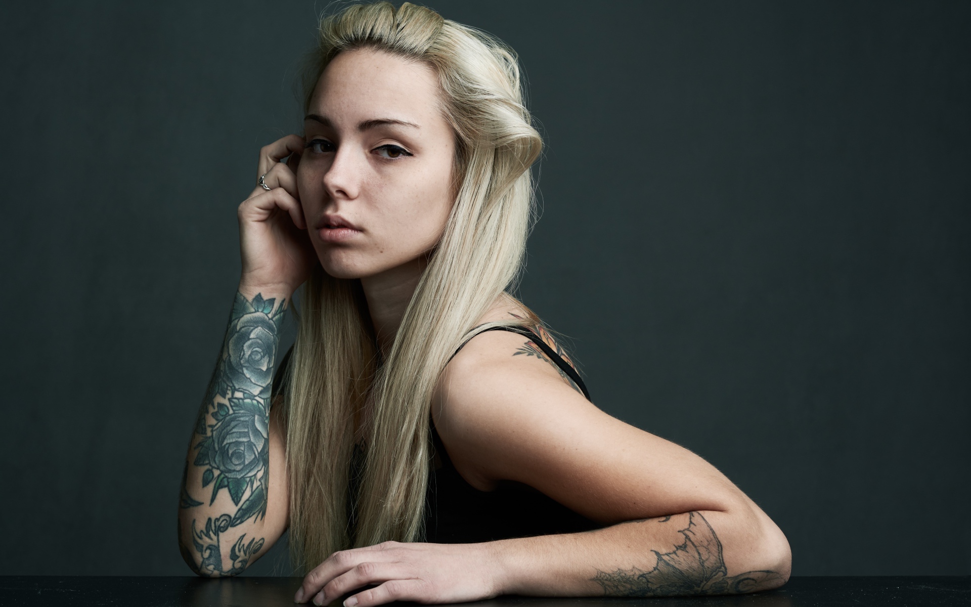 Красивая блондинка с татуировками на теле на сером фоне