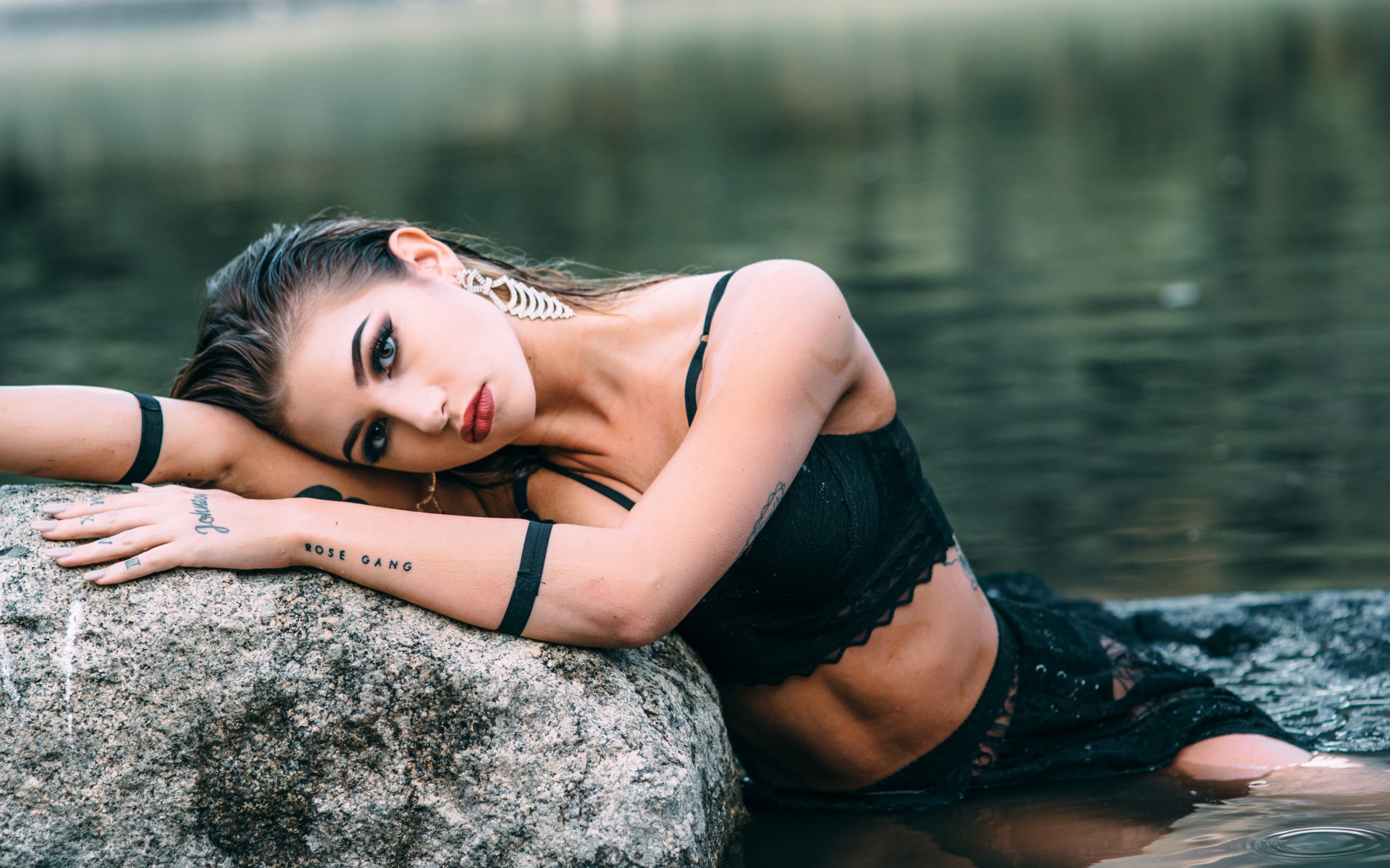 Красивая девушка в черном наряде с татуировками на руках 