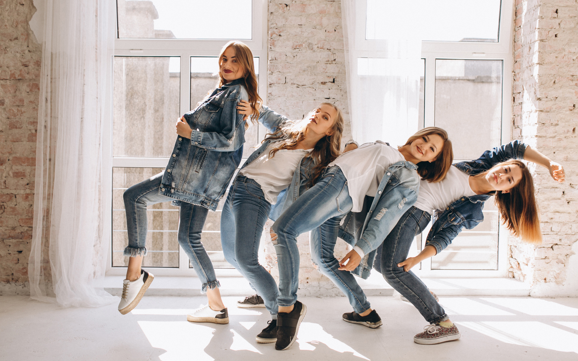 Четыре девушки в джинсовых костюмах занимаются танцами