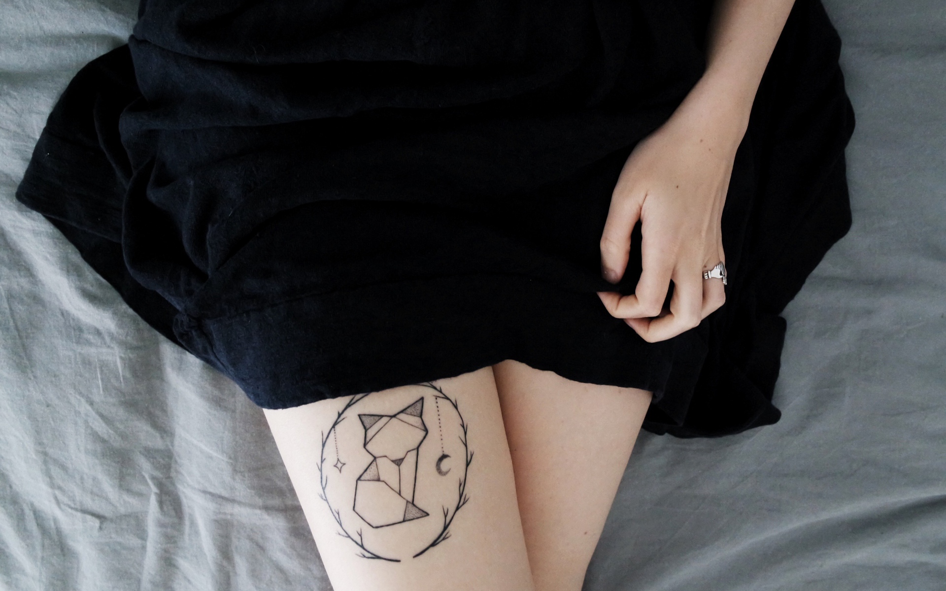 Татуировка лиса на ноге у девушки в черном платье