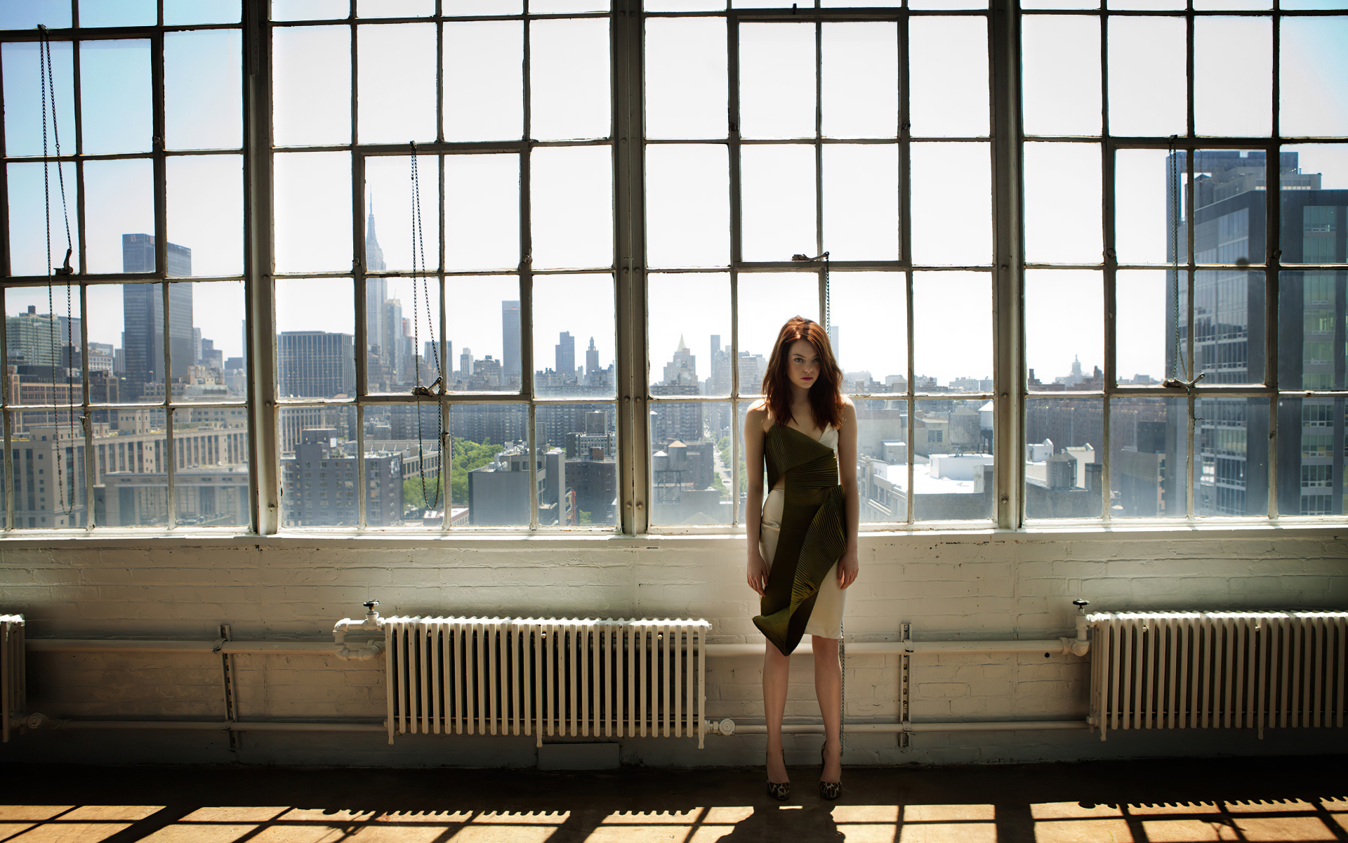 Популярная актриса Эмма Стоун стоит у большого окна