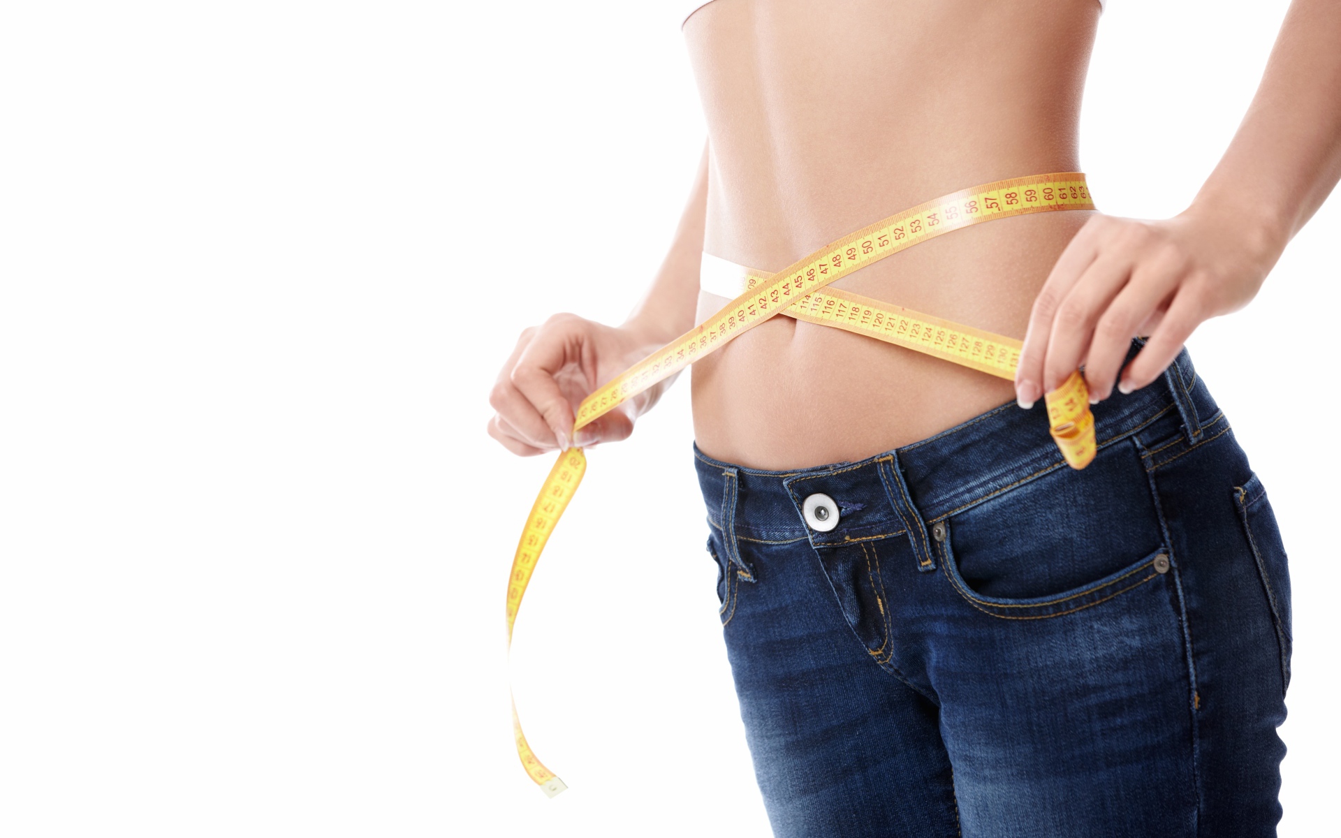 Стройная девушка меряет талию сантиметром 