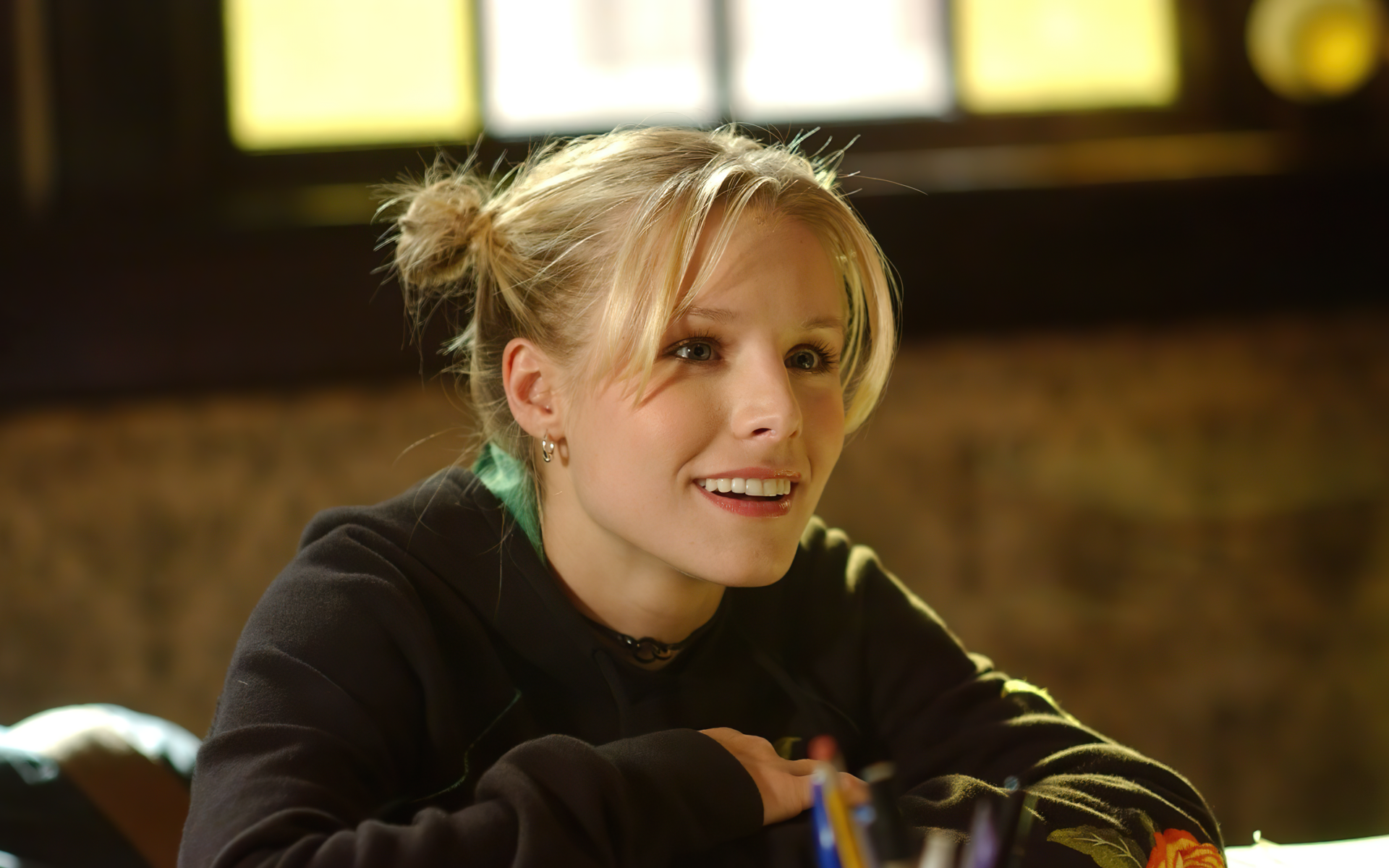 Улыбающаяся актриса Кристен Белл сидит в классе 