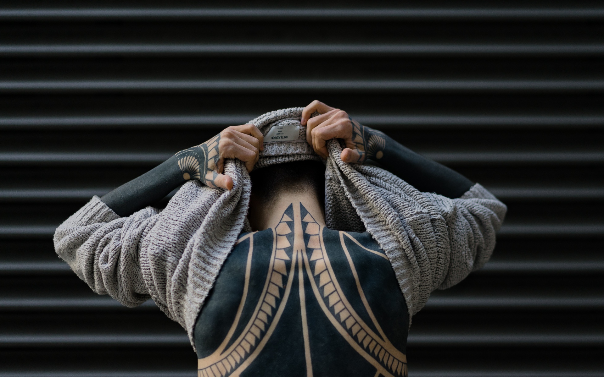 Татуировки на теле мужчины в свитере