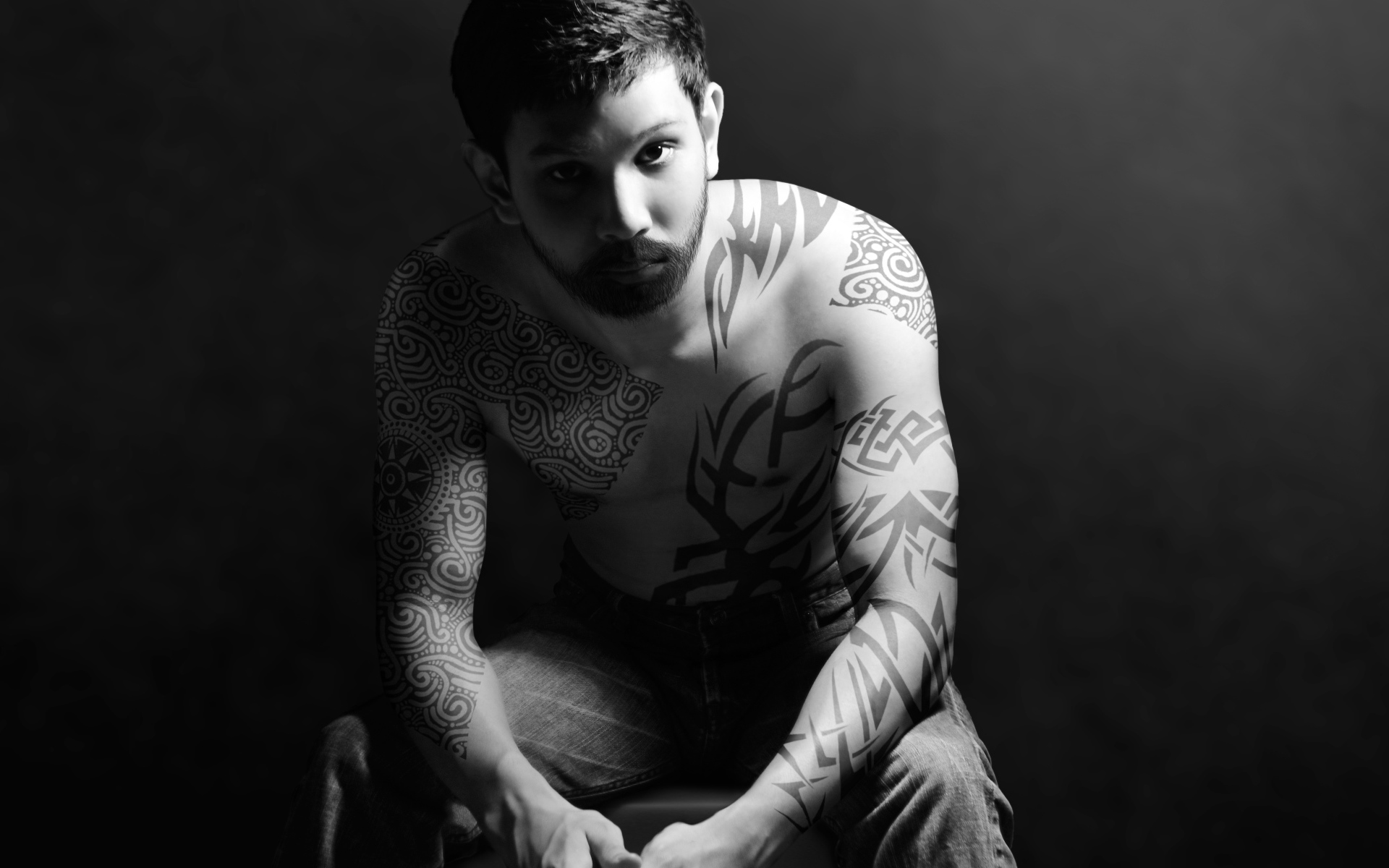 Молодой парень с татуировками на теле на сером фоне