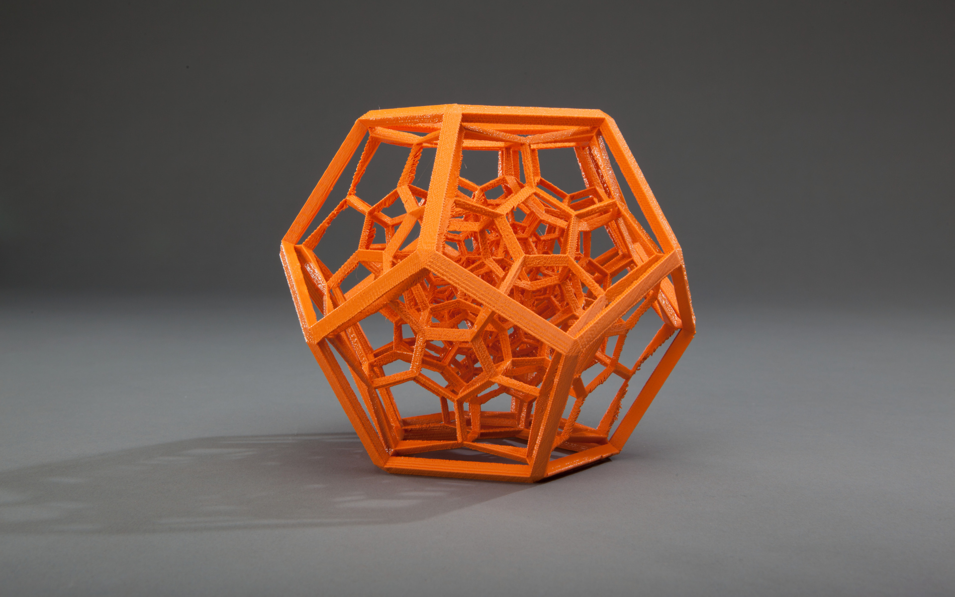 Оранжевый многогранник на сером фоне 3д