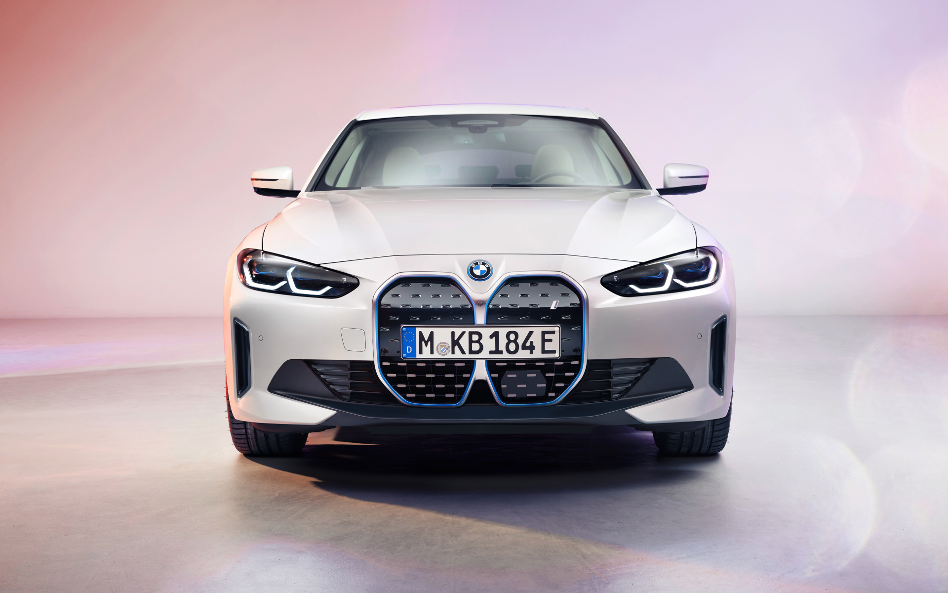Автомобиль BMW I4 2021 года вид спереди на розовом фоне