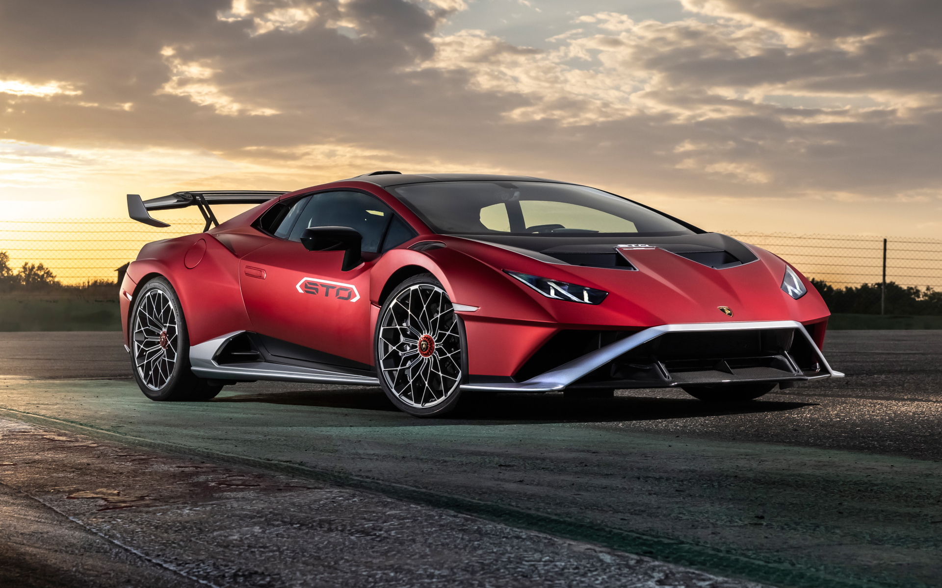 Красный автомобиль Lamborghini Huracán STO 2021 года на фоне неба