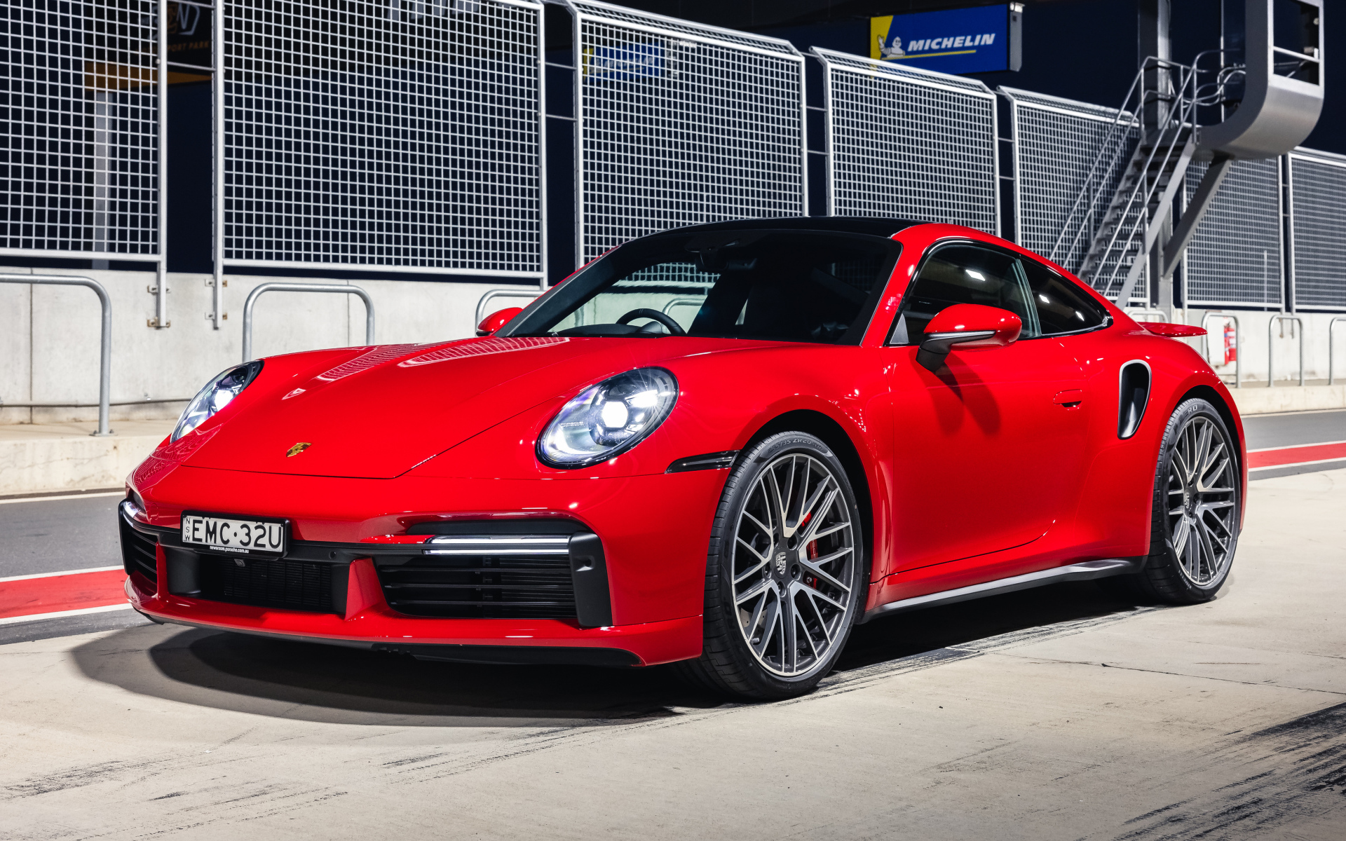 Красный автомобиль Porsche 911 Turbo 2021 года на стадионе