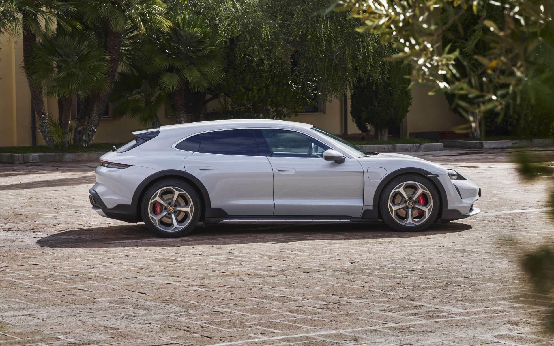 Серебристый автомобиль Porsche Taycan 4S Cross Turismo 2021 года у дома