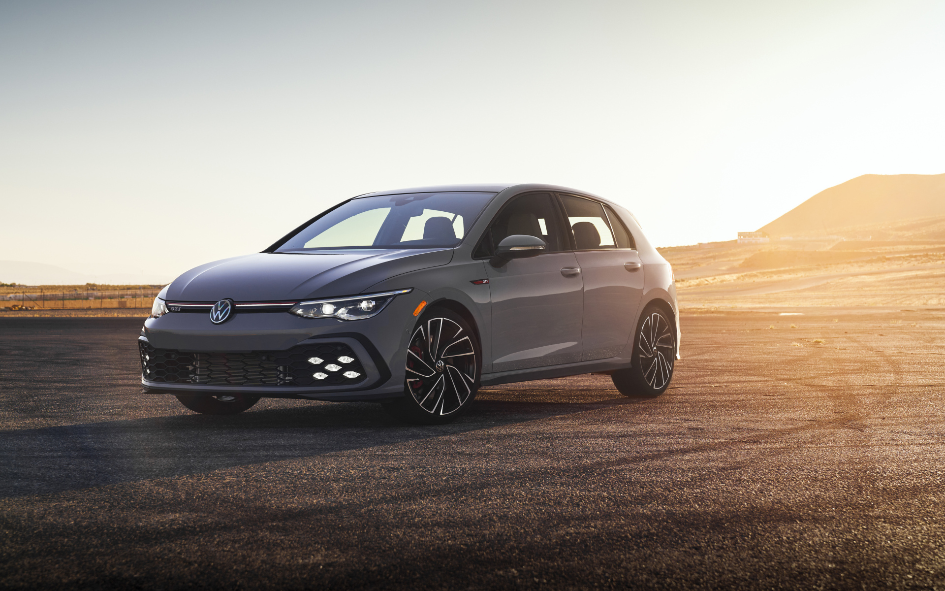 Серебристый автомобиль Volkswagen Golf GTI на фоне заката