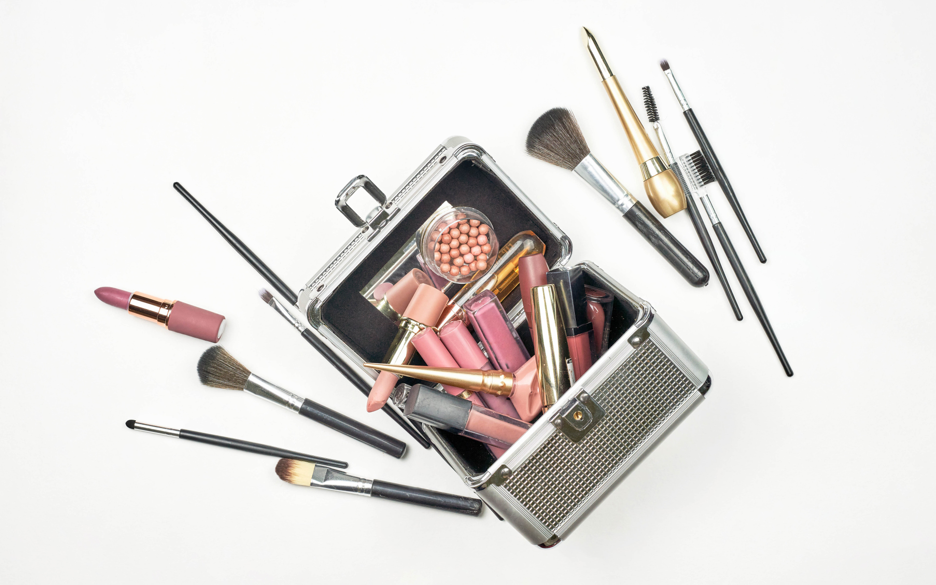 Набор косметики в чемодане на белом фоне