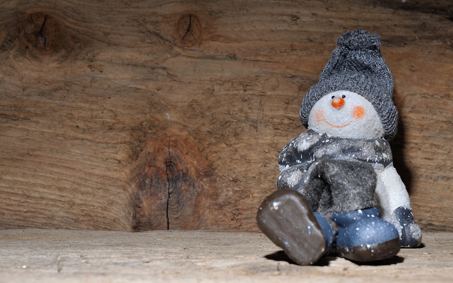 Фигурка снеговик у деревянной стены