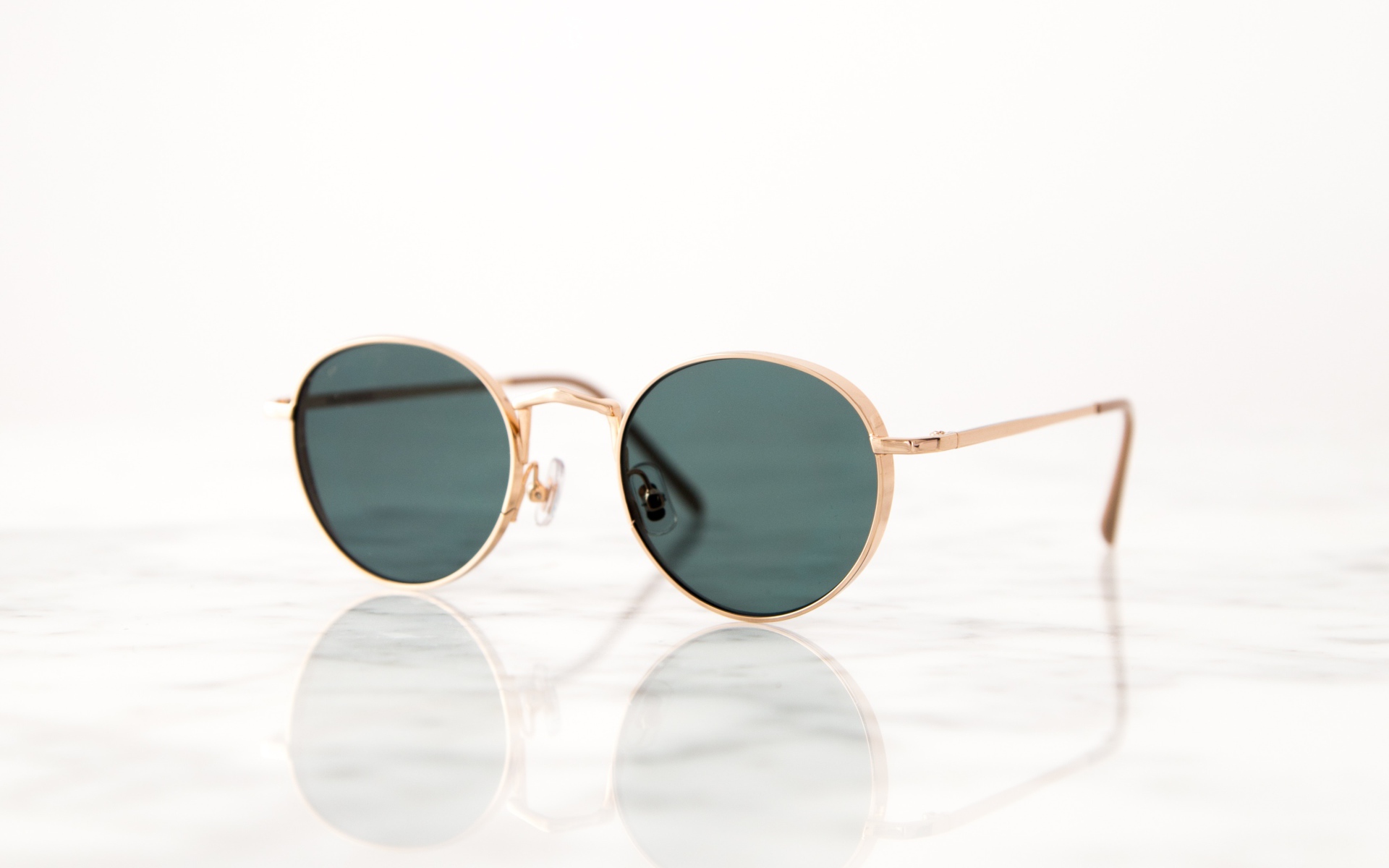 Солнечные очки лежат на зеркальной поверхности