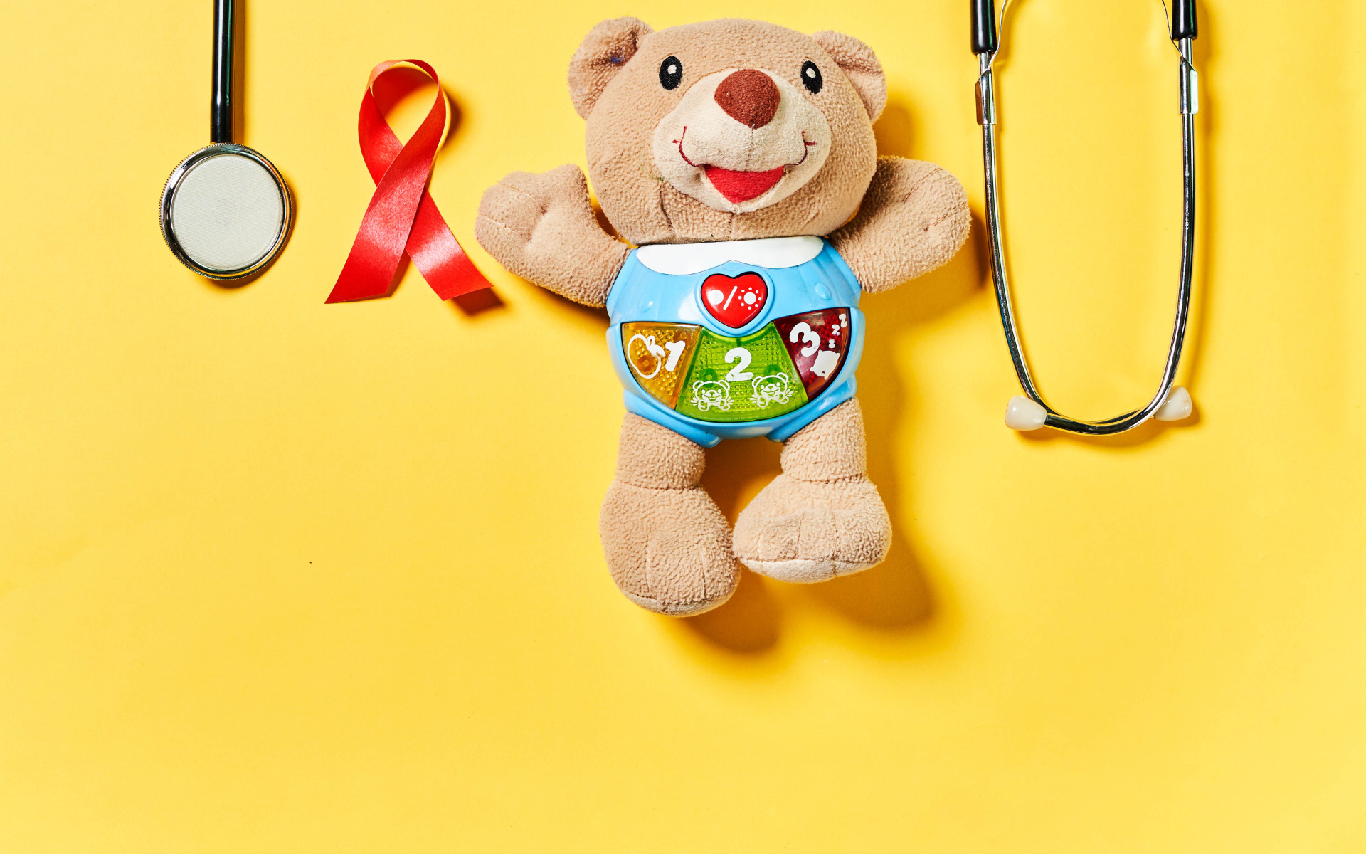 Игрушечный медвежонок с фонендоскопом на желтом фоне 