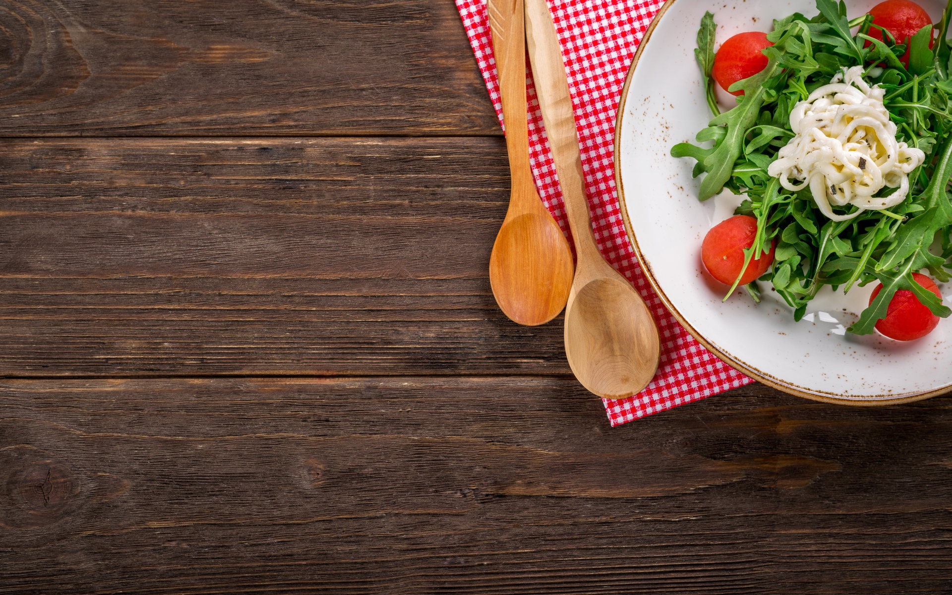 Руккола с помидорами на тарелке с ложками 