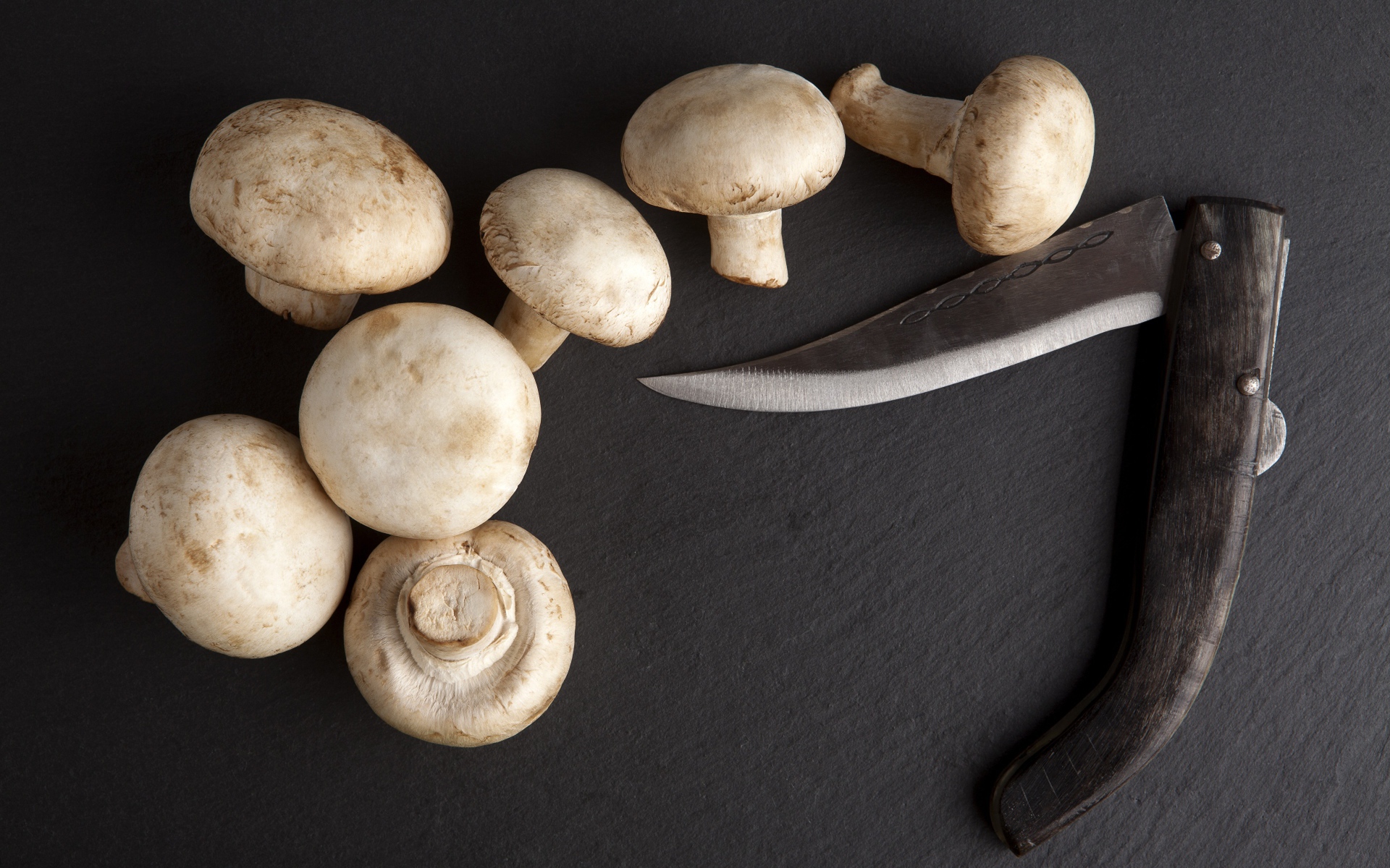 Шампиньоны на сером столе с ножом