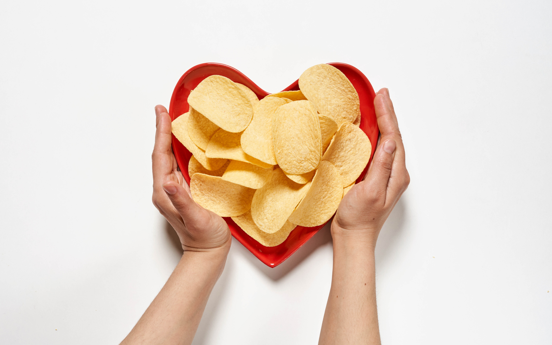 Чипсы в красной тарелке на белом фоне