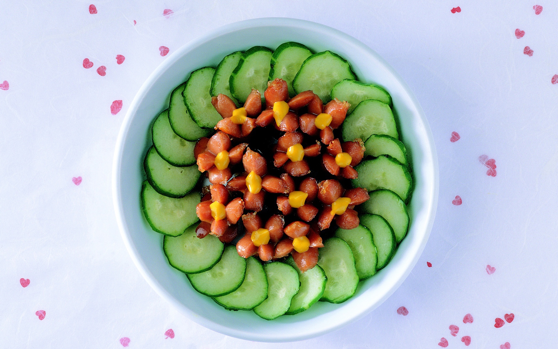 Огурцы с сосисками в тарелке на столе