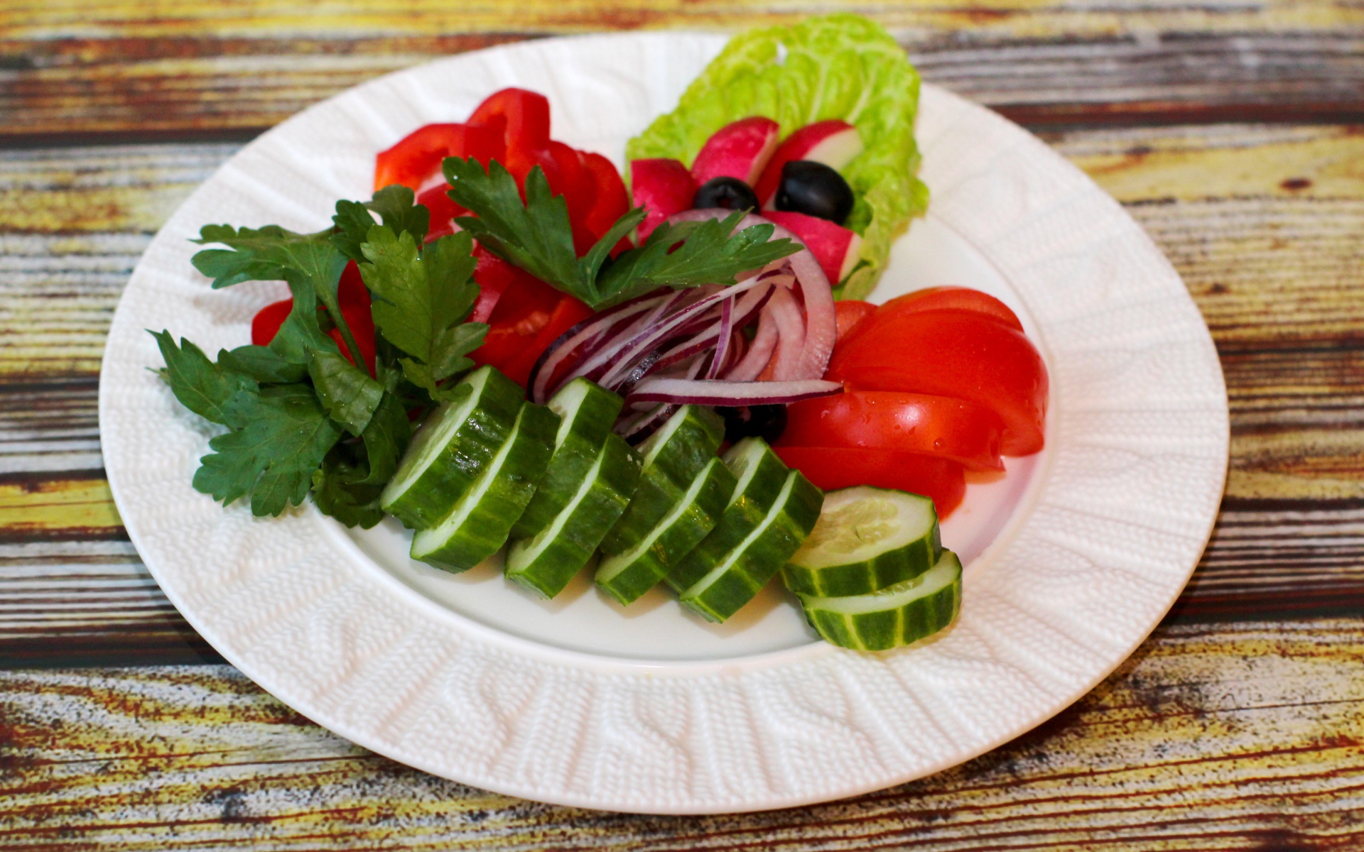 Свежие овощи на белой тарелке на деревянном фоне