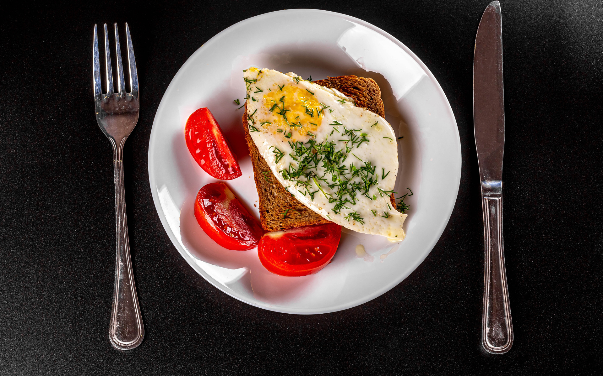 Кусок хлеба с яичницей на тарелке с помидорами