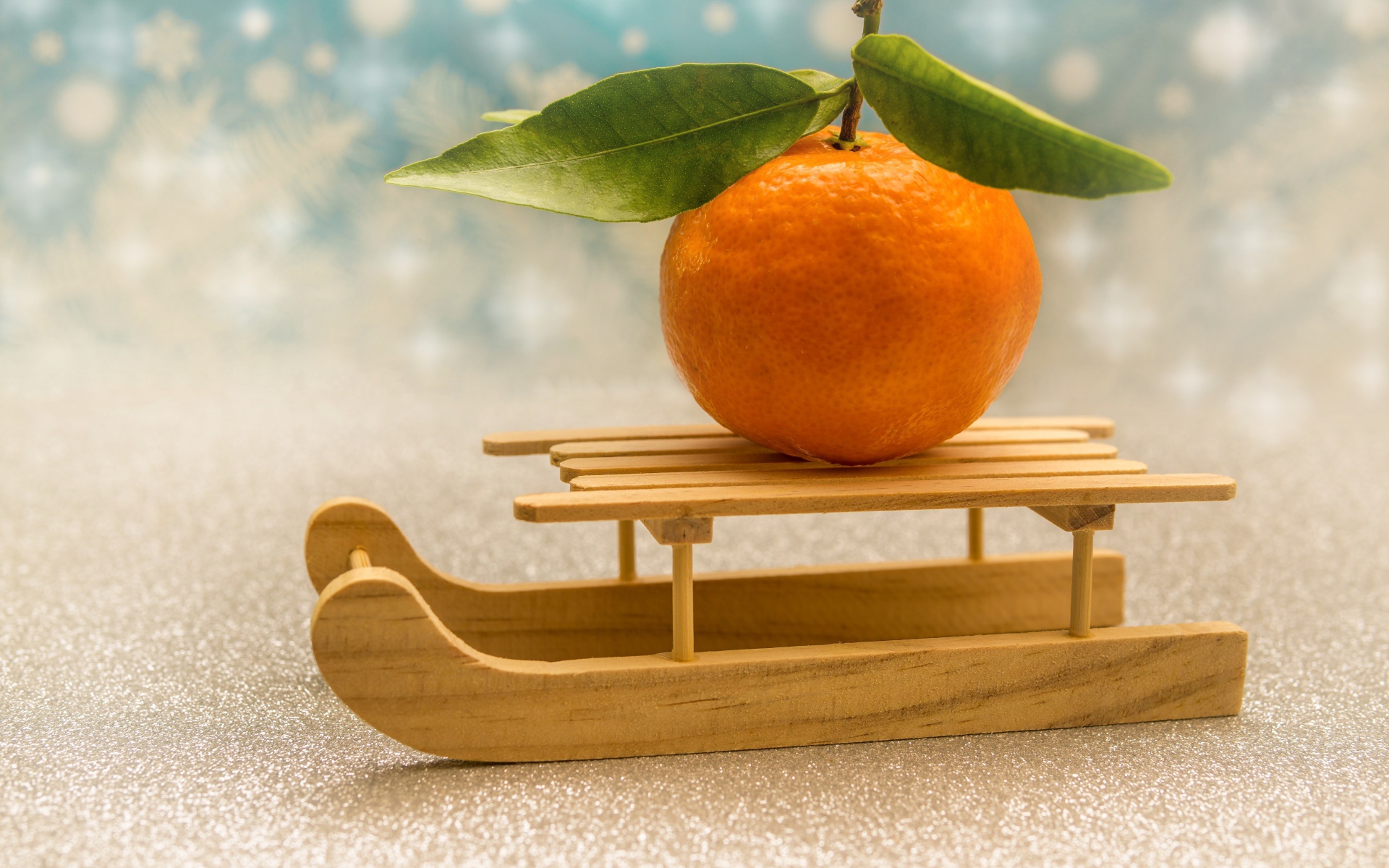 Большой оранжевый мандарин на маленьких санках