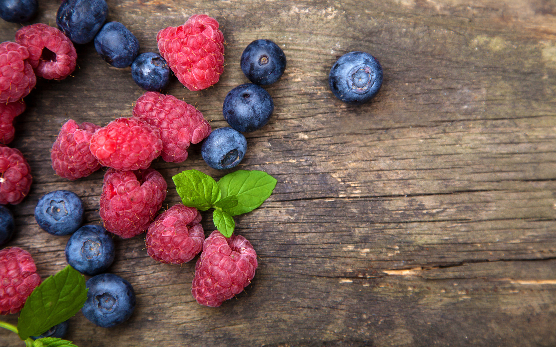 Голубые ягоды черники и красные ягоды малины на деревянном столе