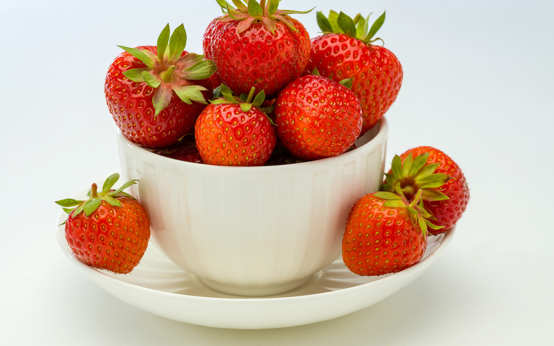 Спелая красная клубника в белой миске с блюдцем