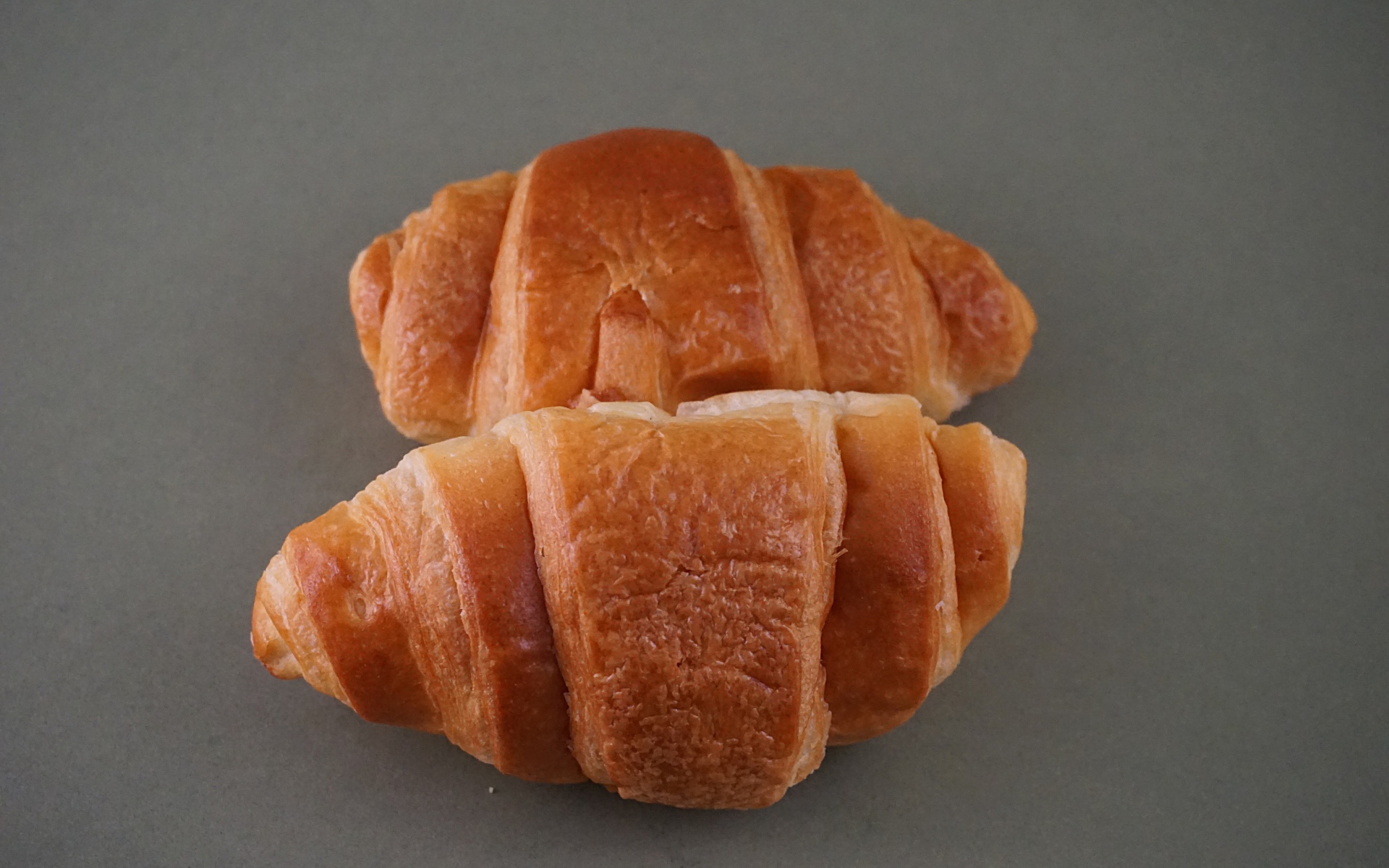 Два свежих круассана на серой поверхности