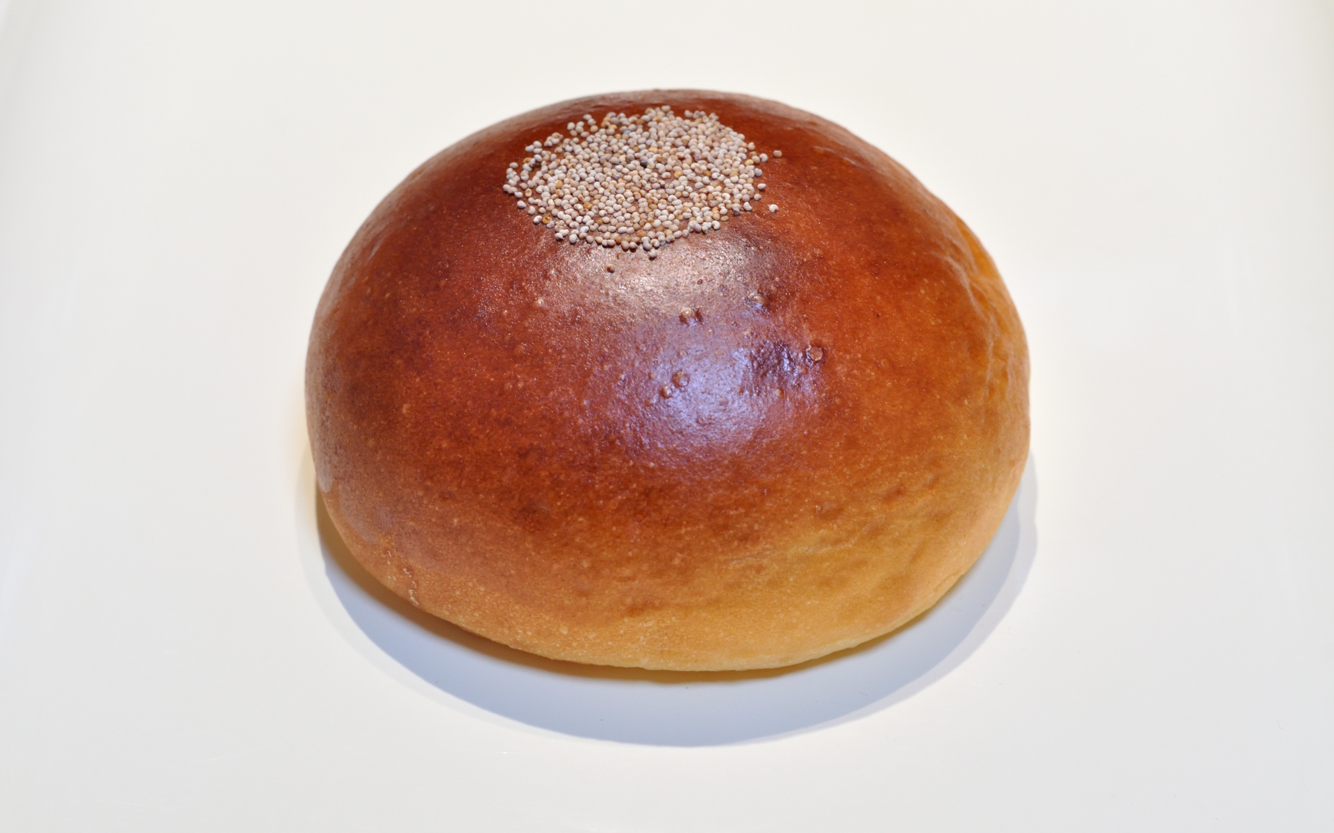 Аппетитная круглая булочка на сером фоне