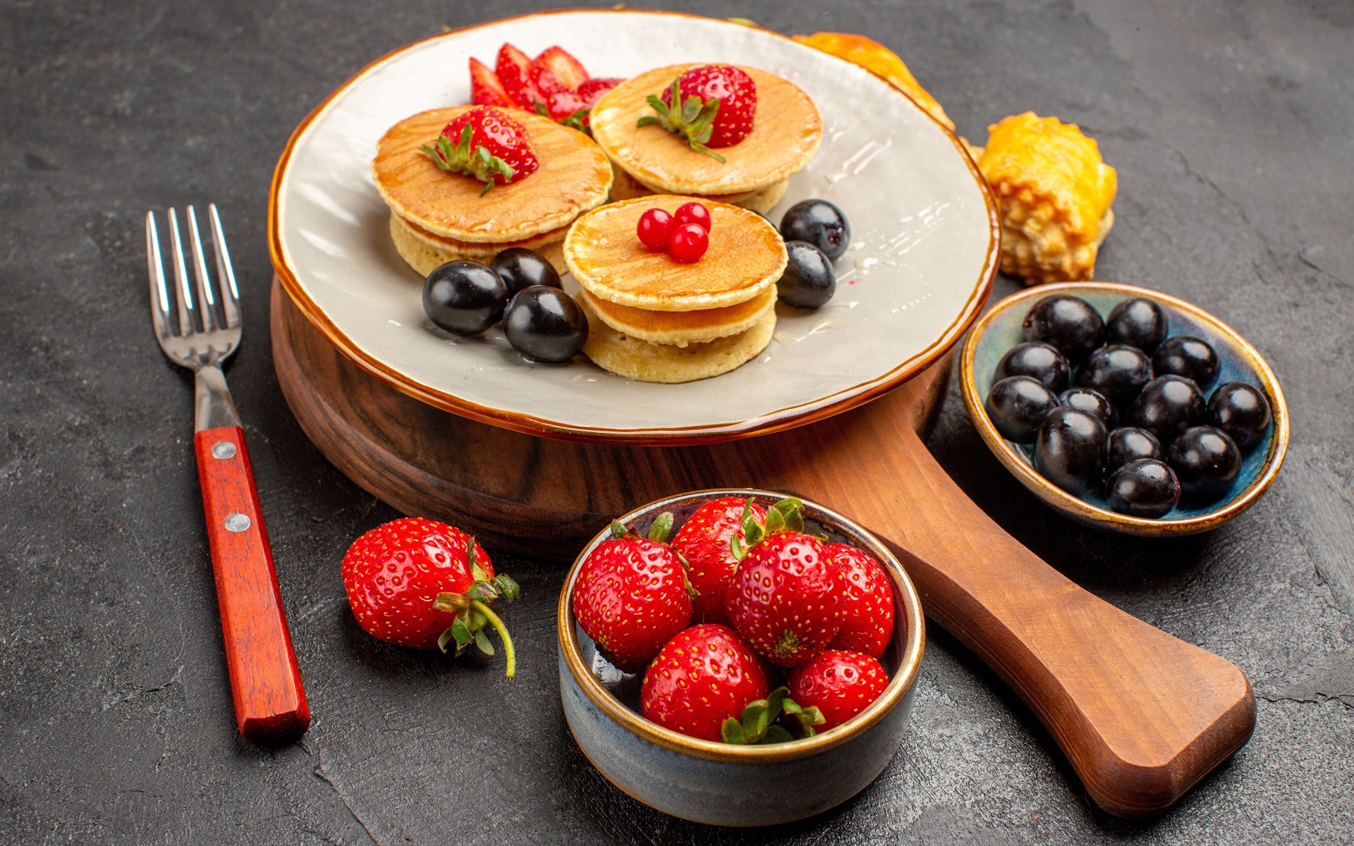 Оладьи с виноградом и клубникой на тарелке 