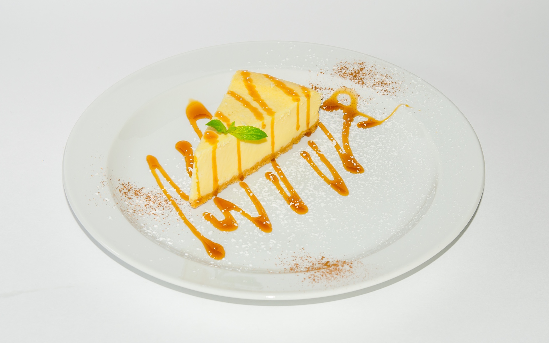 Кусок чизкейка с сиропом на большой белой тарелке 