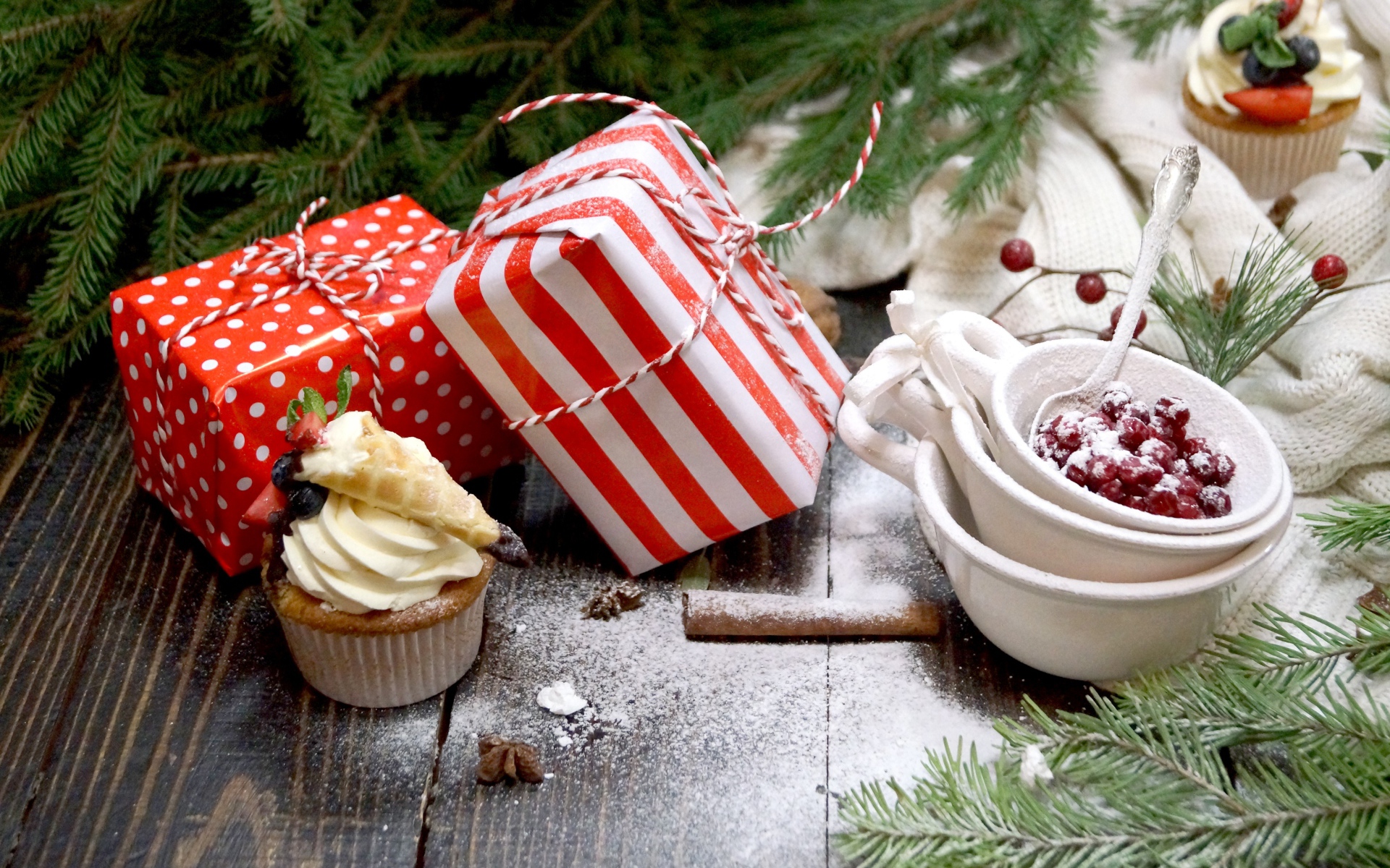 Два подарка на столе с еловой веткой и кексами 