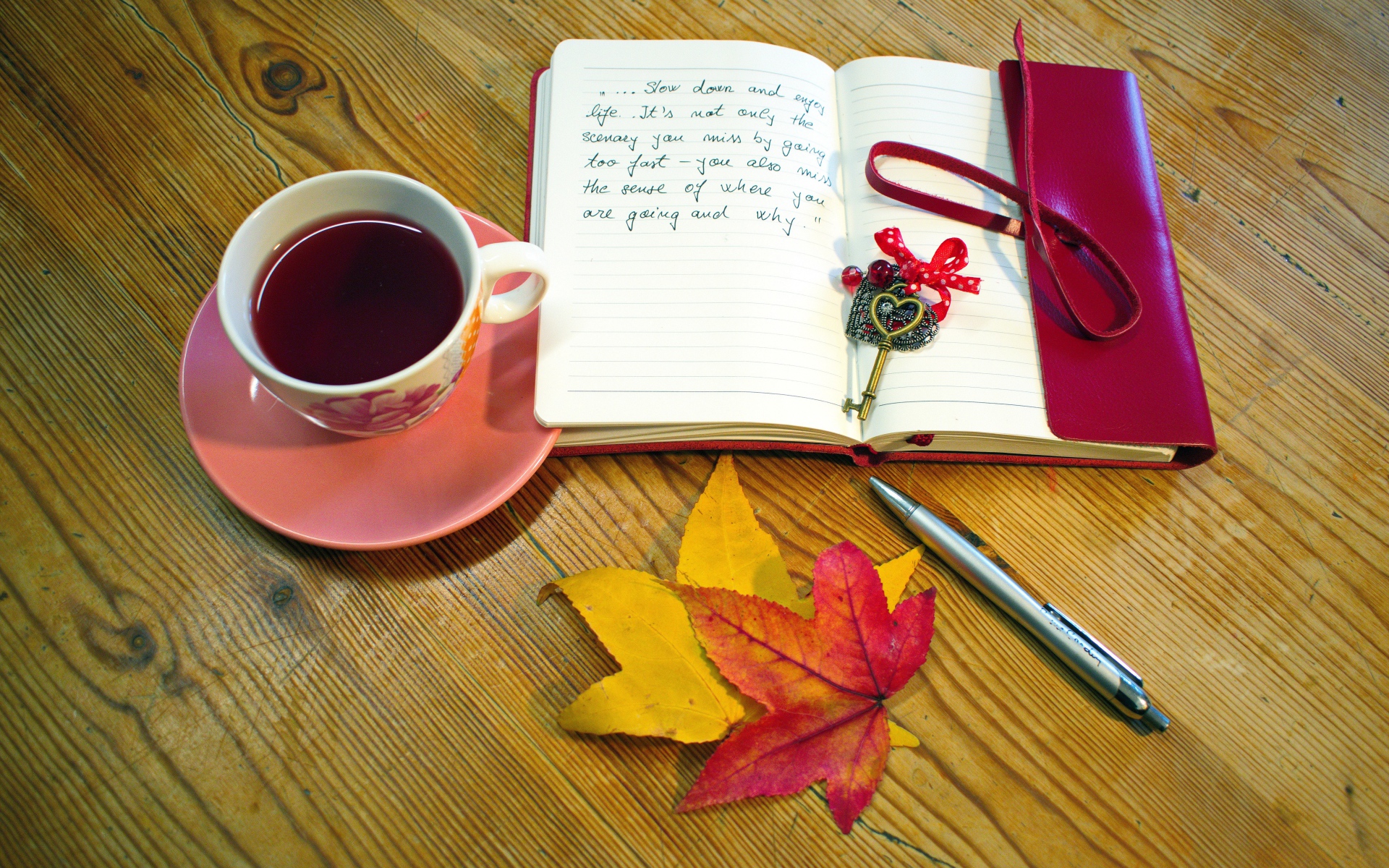 Чашка чая с блокнотом и листьями на столе 