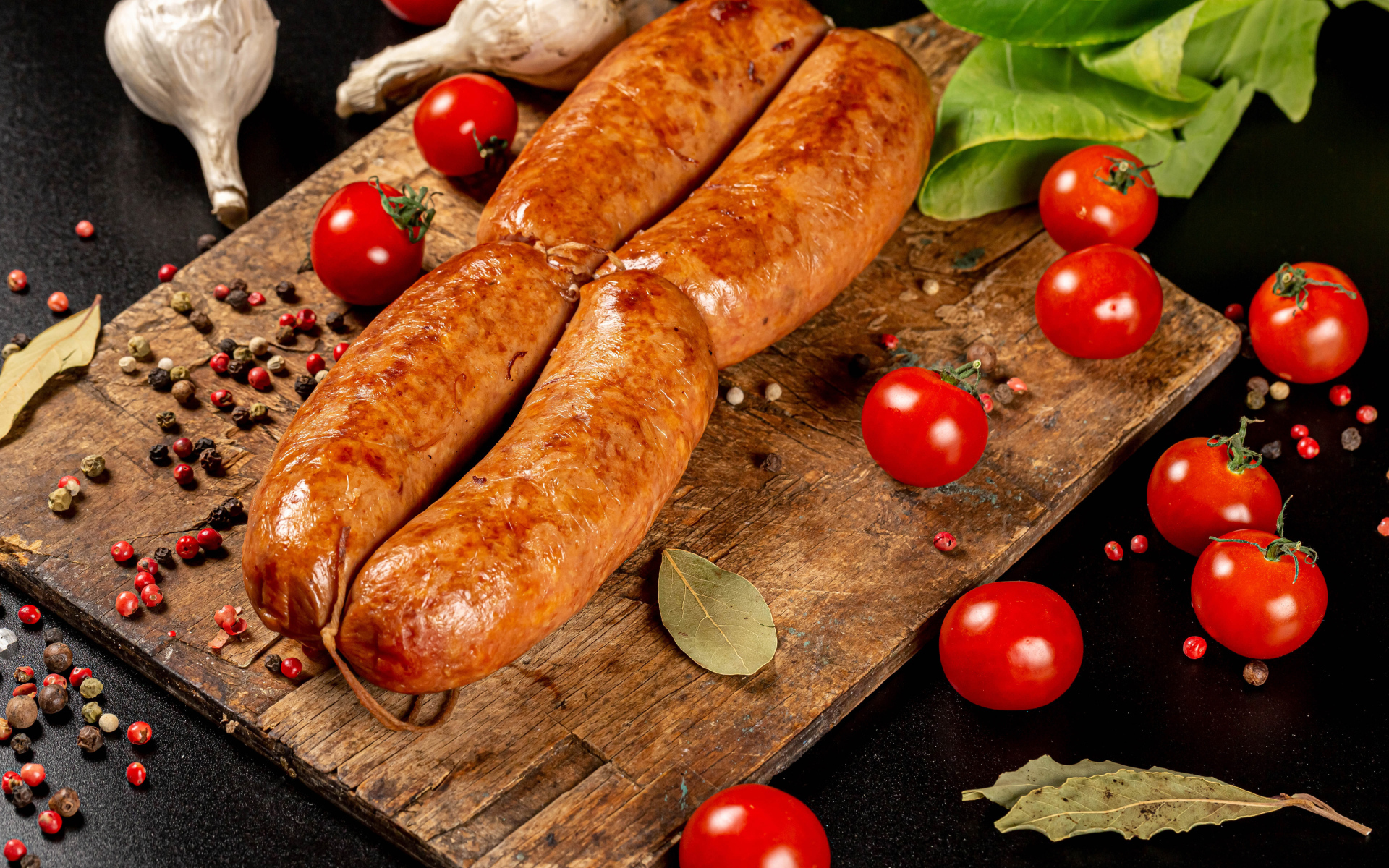 Мясные колбаски на доске с овощами