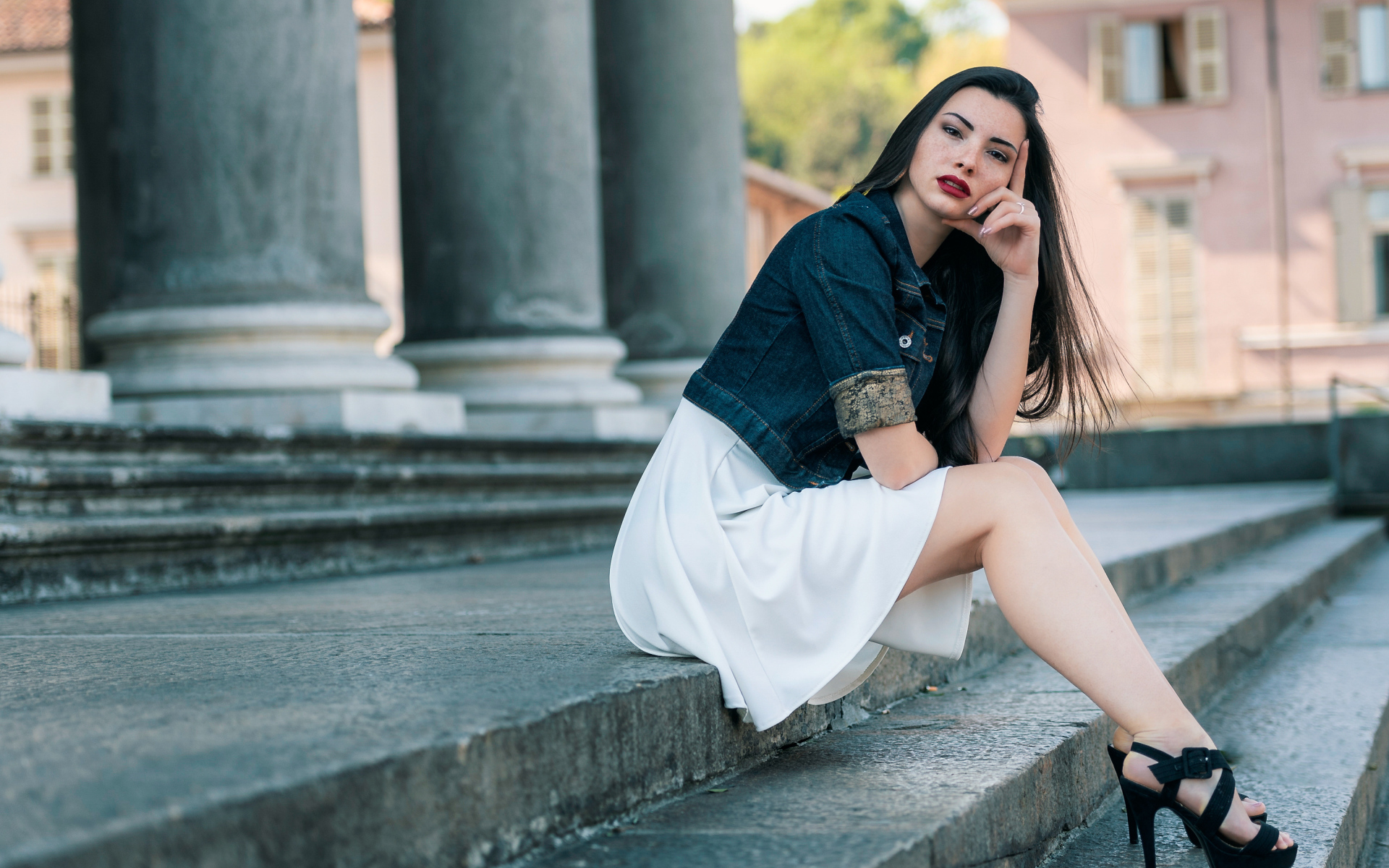 Девушка в белом платье сидит на ступеньках