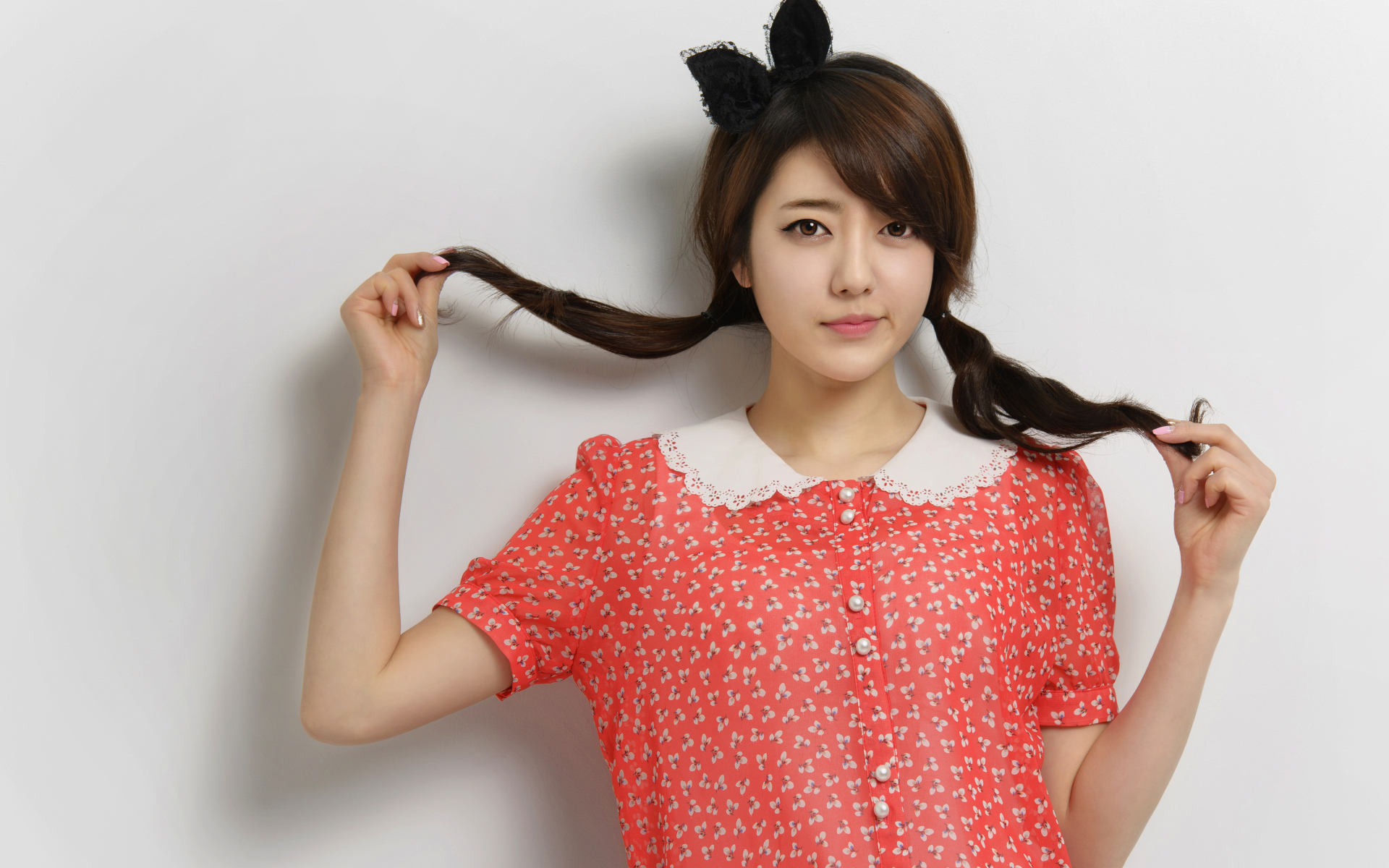 Девушка азиатка в платье стоит у стены 